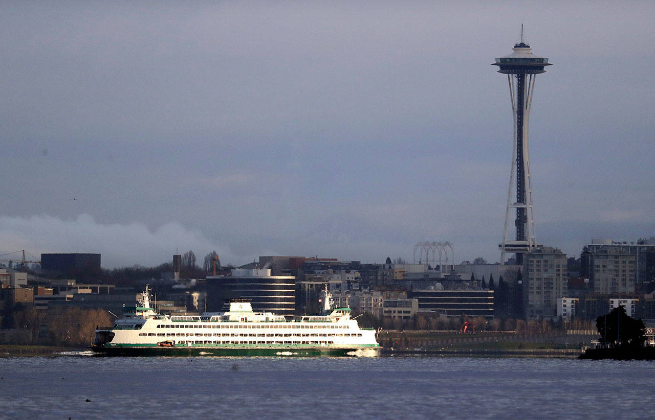 A Washington State ferry heading into Elliott Bay is illuminated by the sun as the city behind remains under clouds in Seattle. (Elaine Thompson/The Associated Press)