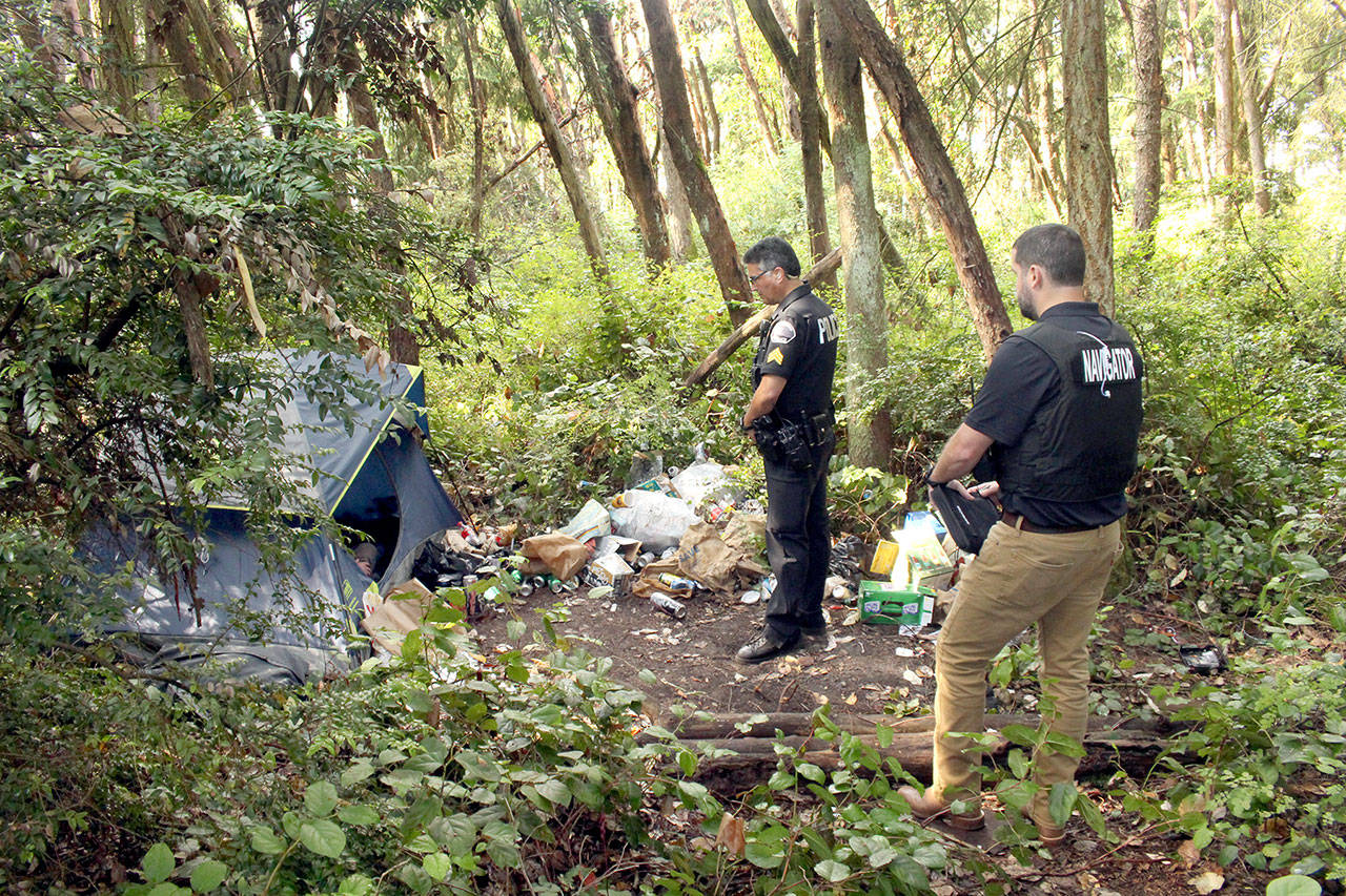 Port Townsend Police Sgt. Troy Surber and Navigator Jud Haynes talk with a homeless man about what help he needs as they prepare to clean out the property the next day. (Zach Jablonski/Peninsula Daily News)