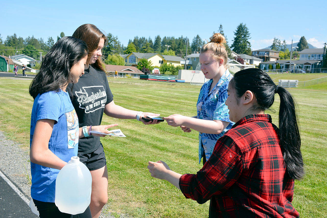 Kathryn Guttormsen and Anne Edwards get their pledge cards punched by Alexus Yeater and Mimi Rose as they complete a lap. (Patsene Dashiell/Port Angeles School District)