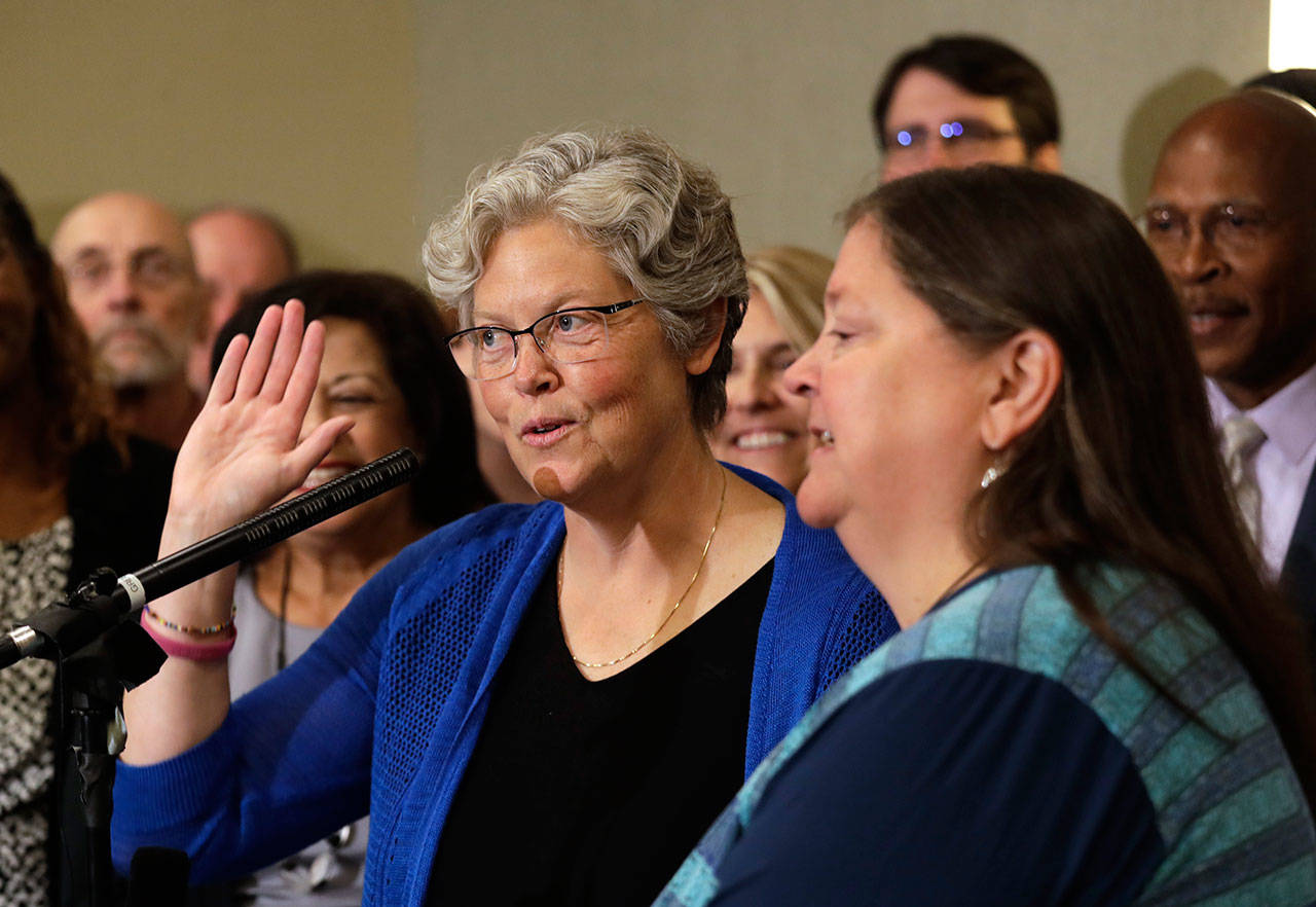 State Rep. Laurie Jinkins, left, D-Tacoma, stands with her wife, Laura Wulf, as she addresses a news conference Wednesday following a caucus meeting and vote by Democrats choosing Jinkins as Washington state’s speaker of the House, the first woman in that role. (Elaine Thompson/The Associated Press)