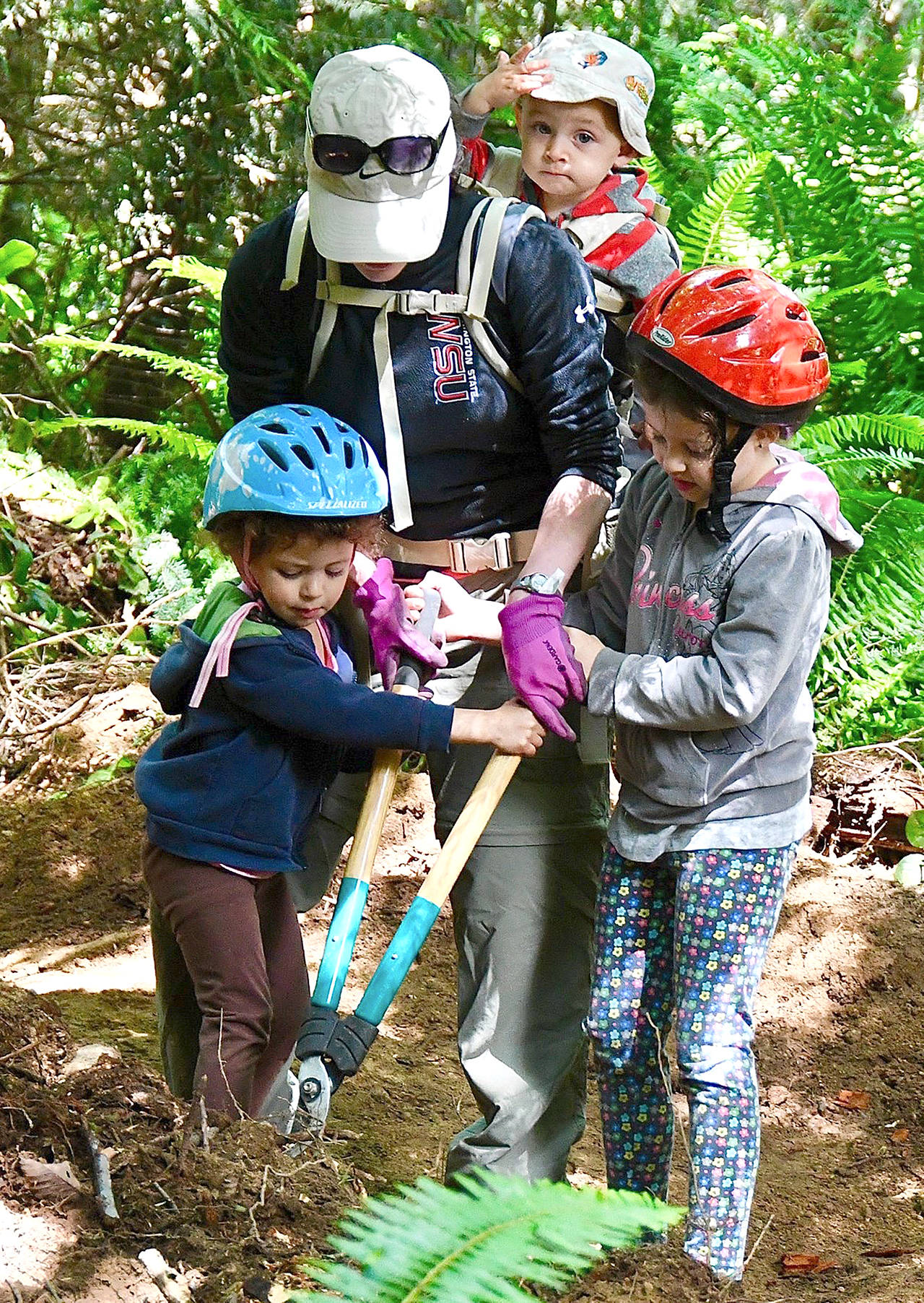 Photo: Jay Cline                                 Top Left Trails Co-Op member Beth Sandoval, center, is assisted during a recent work party at the Colville Mountain Bike Skills Park by her children Eliana Sandoval, left, Cambria Sandoval and Julio Sandoval (wearing hat).