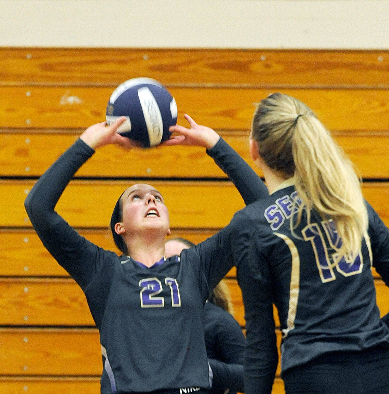 Michael Dashiell/Olympic Peninsula News Group With teammate Kendall Hastings looking on, Sequim junior Kalli Wiker (21) looks to set a teammate against Bremerton during the Wolves’ three-game sweep of the Knights.