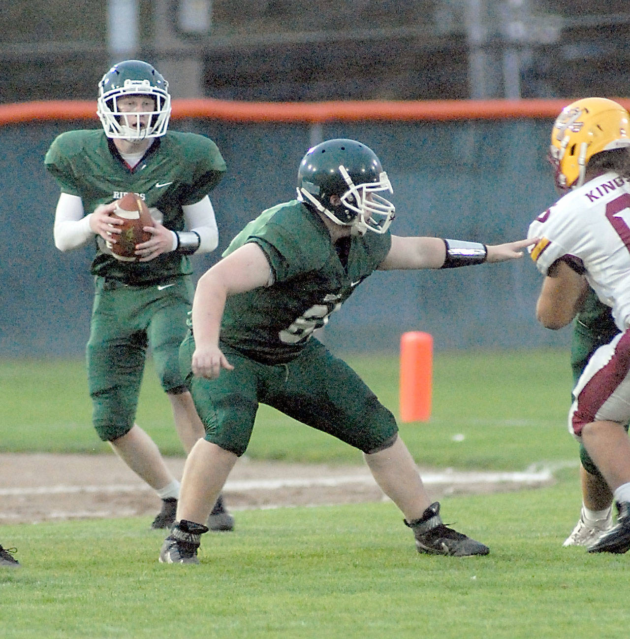 Keith Thorpe/Peninsula Daily News Port Angeles quarterback Daniel Cable drops back to pass as defensive lineman Aiden Cornish fends off the Kingston defense on Friday night at Port Angeles Civic Field.