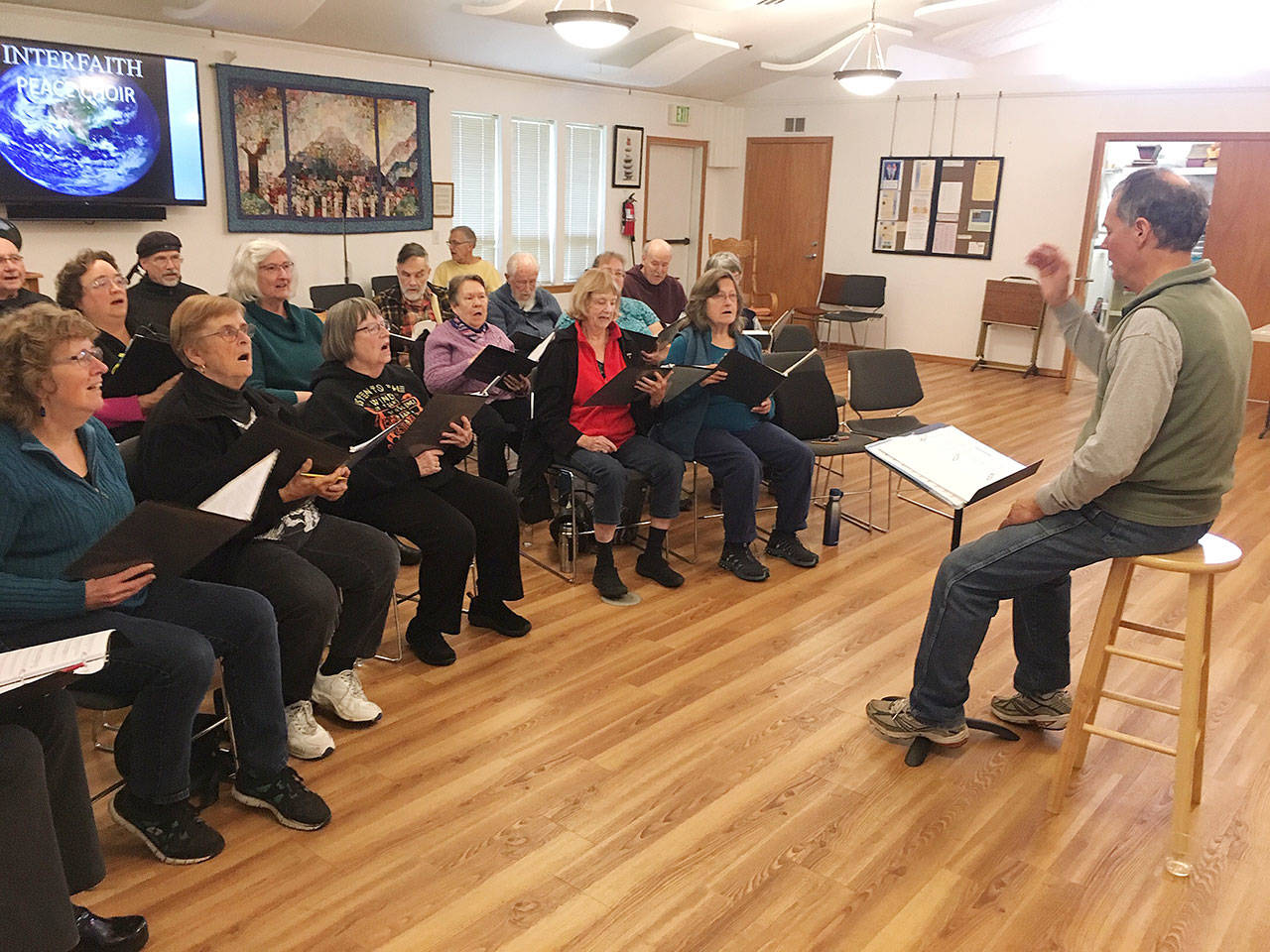 Joel Yelland directs the Interfaith Clallam County Peace Choir in a recent rehearsal.