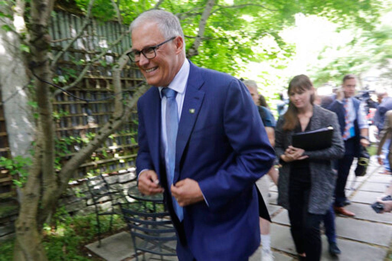 Gov. Jay Inslee heads out after speaking with reporters Aug. 22 in Seattle. (Elaine Thompson/The Associated Press)