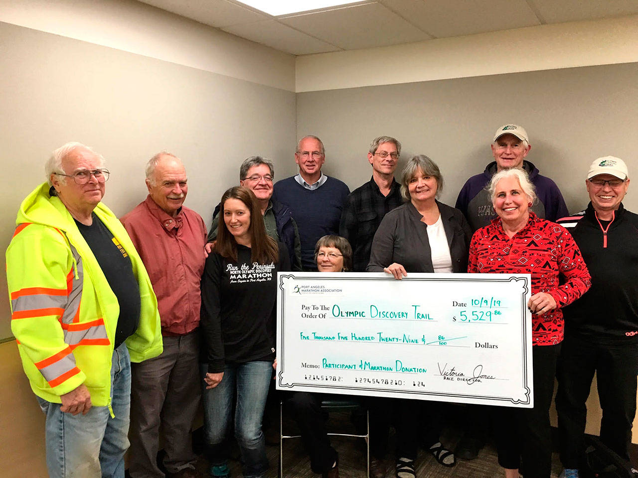 Members of the Peninsula Trails Coalition recently gathered to accept a check for $5,529 from race director Victoria Jones of the North Olympic Discovery Marathon. Pictured are, from left, Vice President Gordon Taylor, Bob Anundson, Jones, Treasurer John Dolansky, Andy Marr, Jan Whitlow, Vice President Bob Lake, Molly Erickson, Merrily Mount, Jeff Selby and Brian Anderson. Not pictured are Jeff Bohman, president of the Olympic Trails Coalition, and Bob Petersen, board member of the trails coalition.