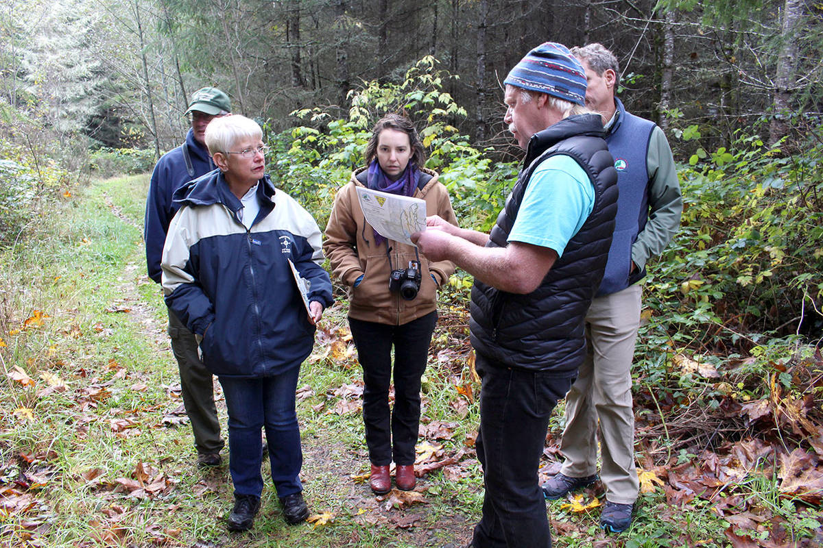 Jefferson County Advisory Board member Vern Bessey checks the trail map along with, from left, board members Tim Rensema and Marianne Walters, Libby Masaracchia of county Public Works and manager of Jefferson County Parks and Recreation, Matt Tyler while they walk through the Silent Alder Loop Trail in Chimacum on Wednesday morning during their annual parks tour. (Zach Jablonski/Peninsula Daily News)