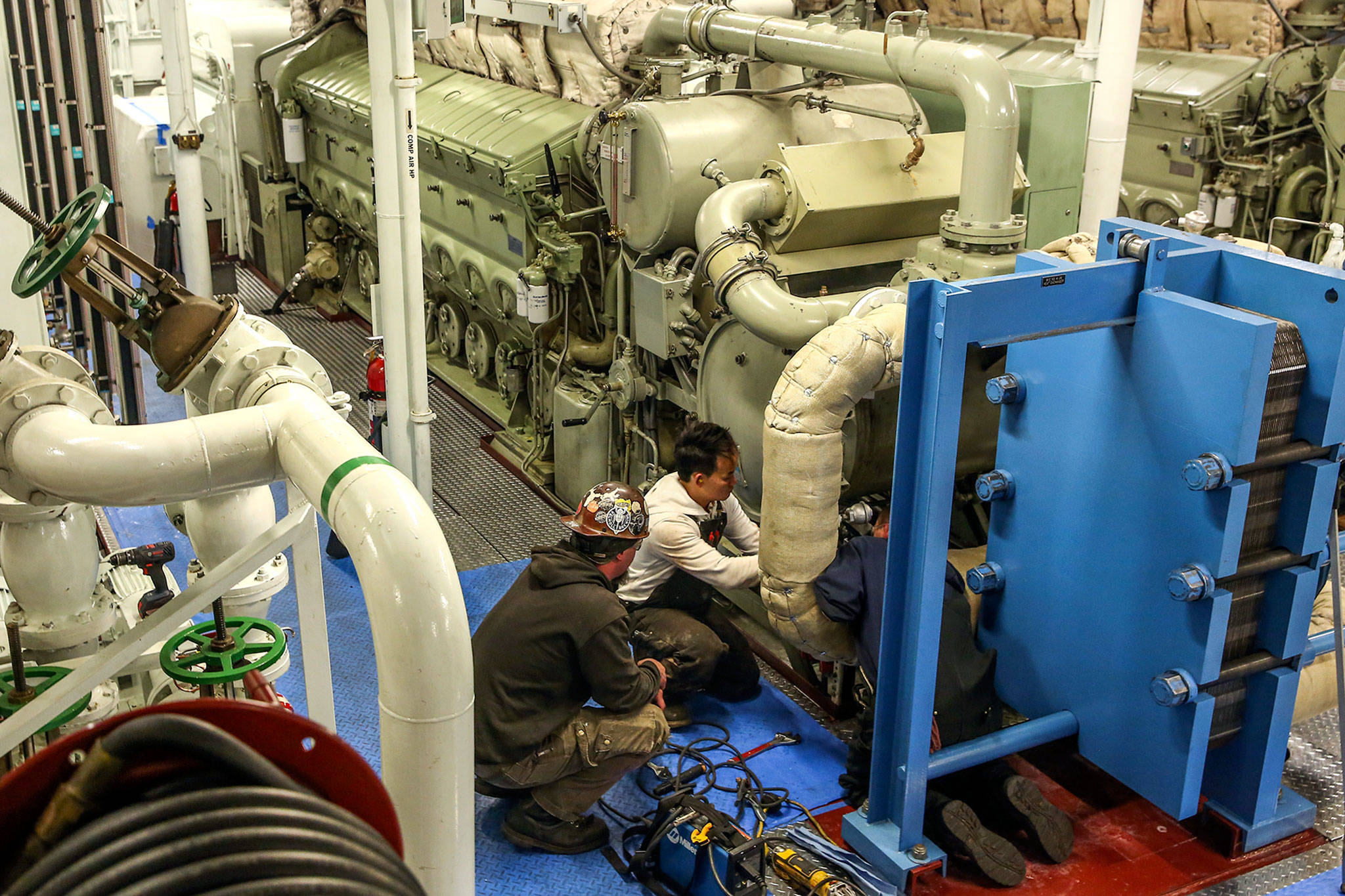 Crews work to replace and refit a water filter system aboard the MV Puyallup at the Eagle Harbor Maintenance Facility on Bainbridge Island last Thursday. (Kevin Clark/Everett Herald)