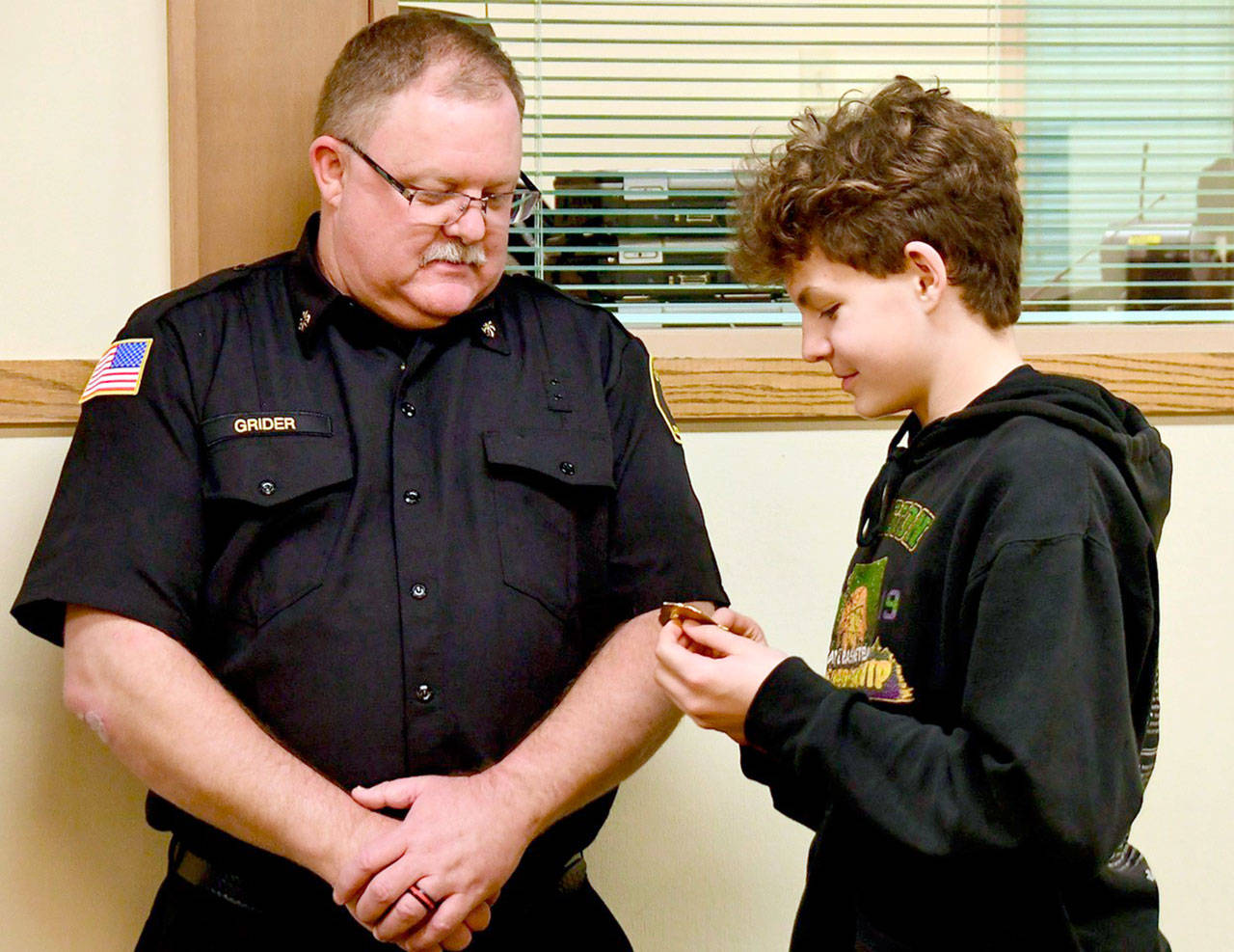 Deputy Fire Chief Justin Grider has his badge pinned on by his son Charlie at a Clallam 2 Fire Rescue Board of Commissioners meeting.