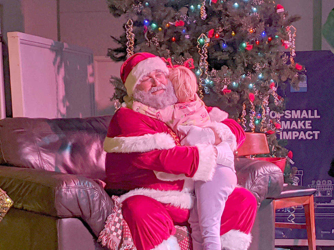 Tove Brevik, 4, hugs Santa after getting a photo with him at the “Reindeer Region at the Legion” at the American Legion in Port Townsend. (Zach Jablonski/Peninsula Daily News)