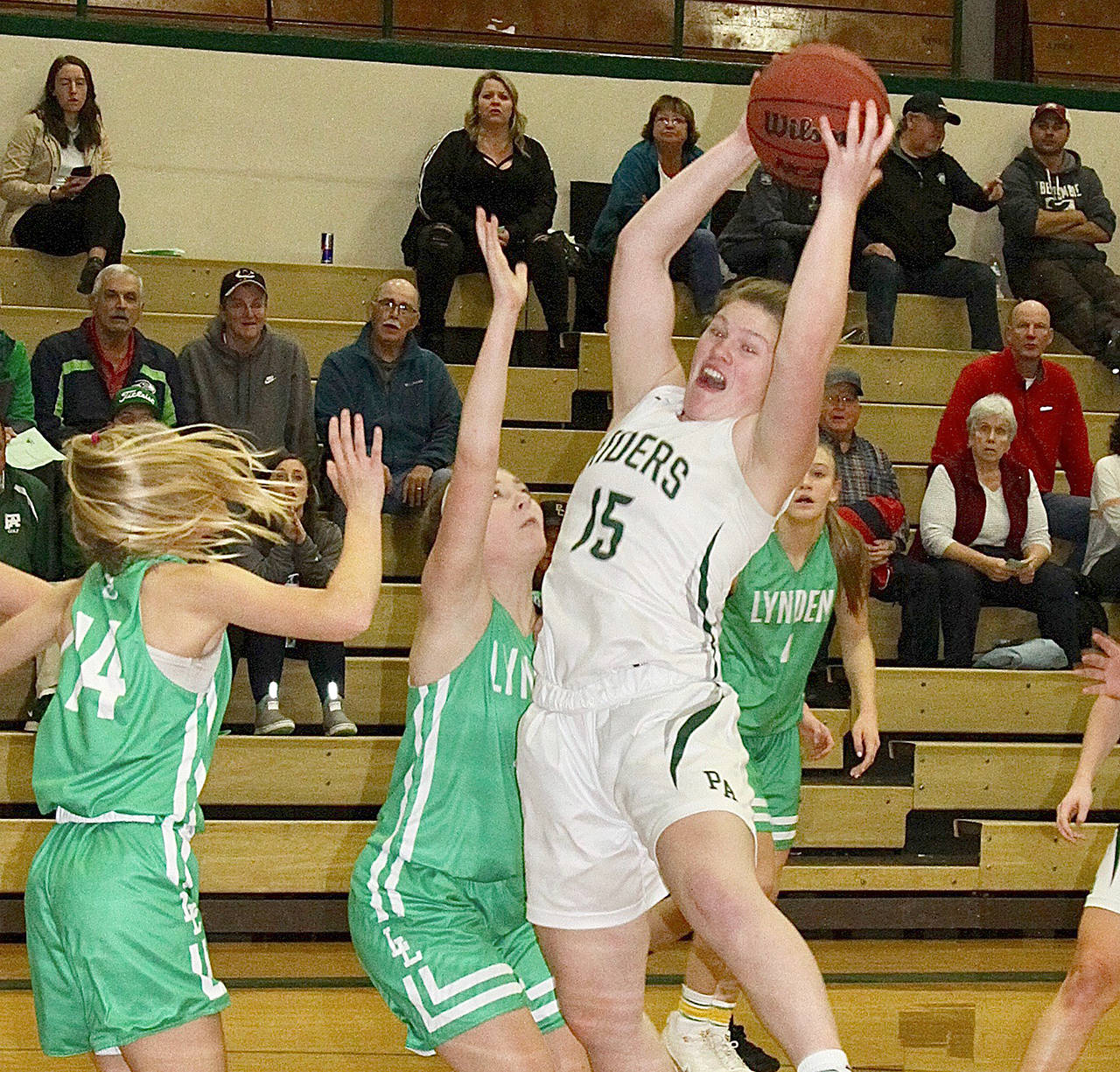 Port Angeles’ Myra Walker (15) goes up for a rebound against the Lynden Lions’ Liv Tjoelker during the Roughriders’ 46-42 loss Tuesday. (Dave Logan/for Peninsula Daily News)