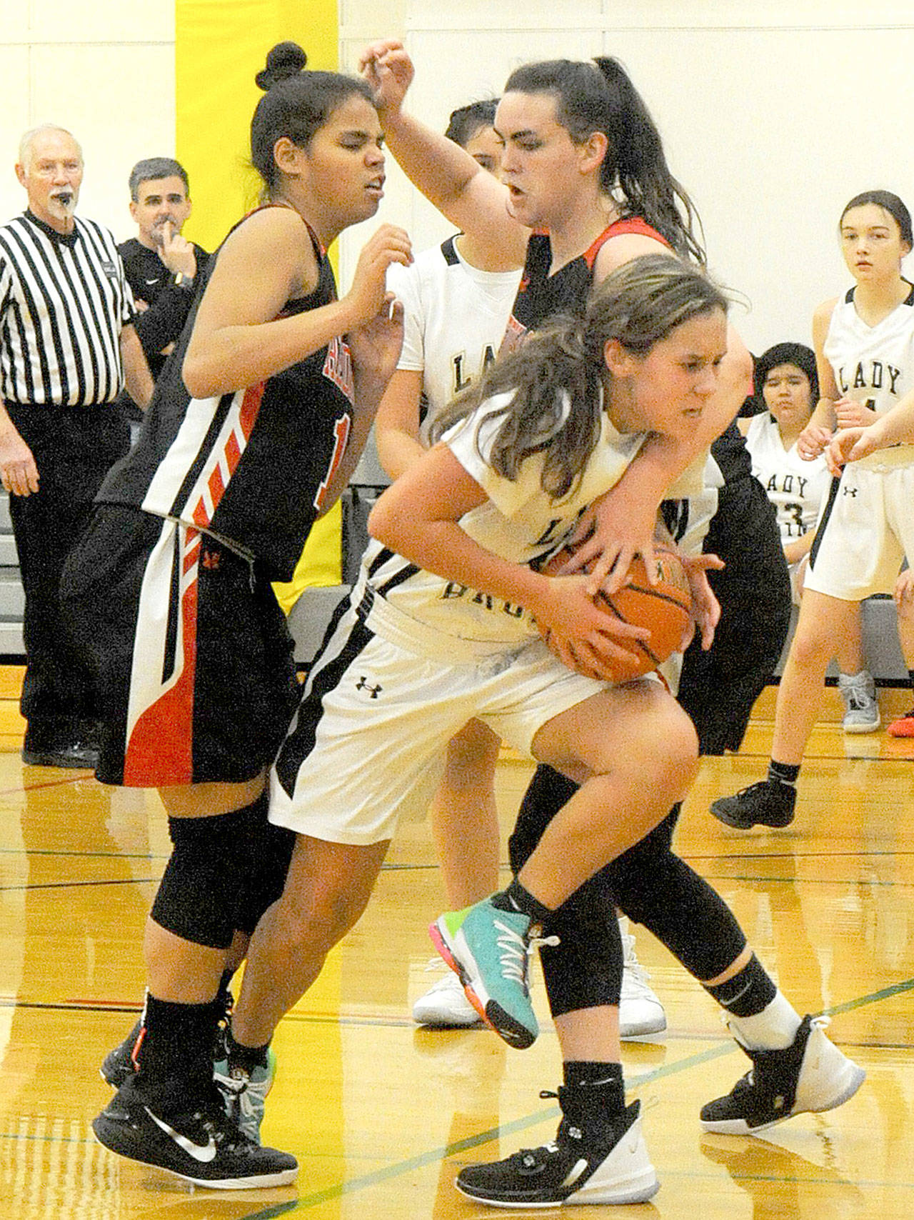 Clallam Bay’s Amber Swan attempts to escape the pressure applied by Redhawks Gina Brown, left, and Izzy Hammett as she drives the lane. (Lonnie Archibald/for Peninsula Daily News)