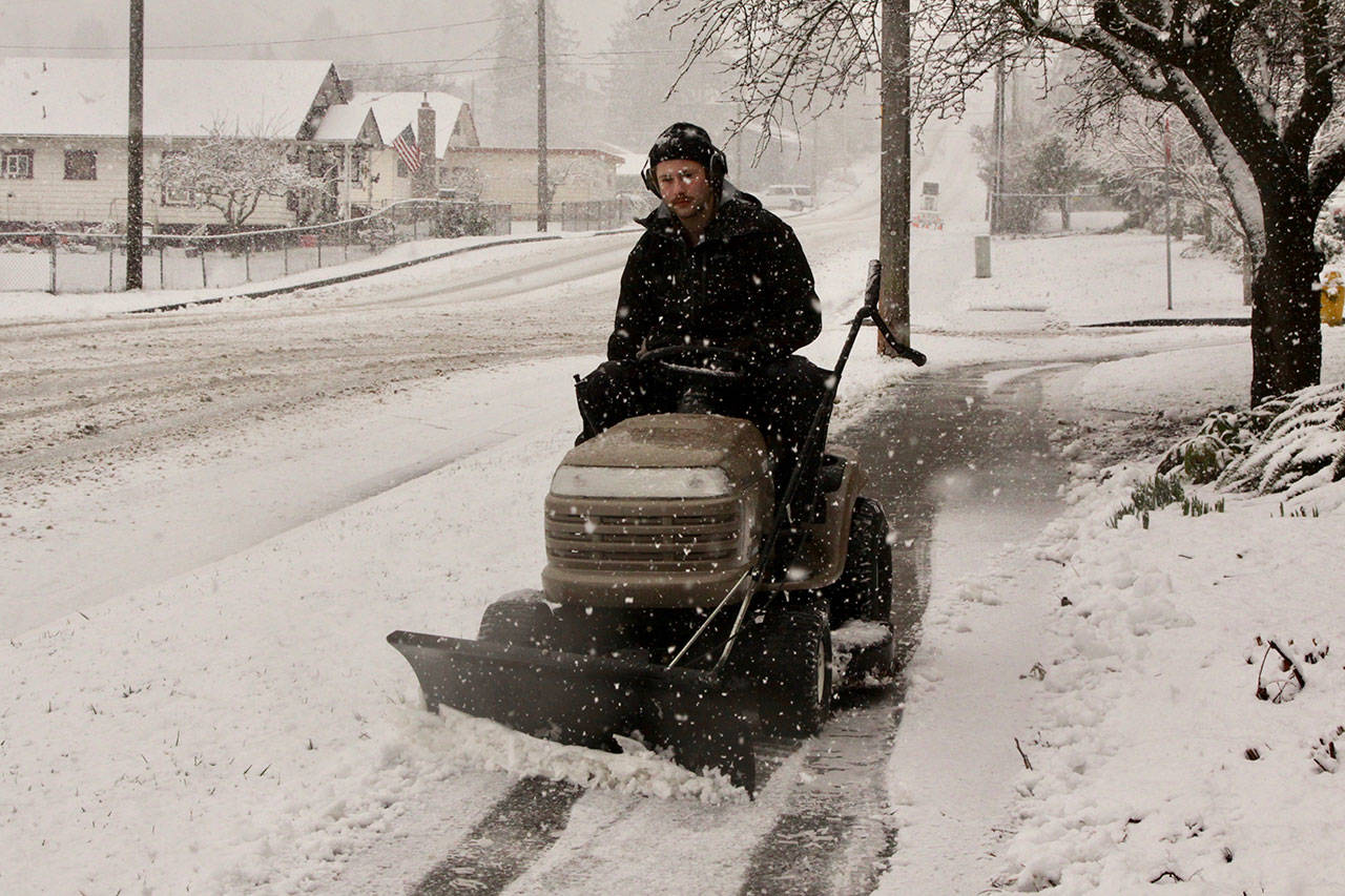 Joshua Bolton of the North Olympic Library System plows the sidewalk on Peabody Street next to the Port Angeles Library on Monday morning. (Dave Logan/for Peninsula Daily News)