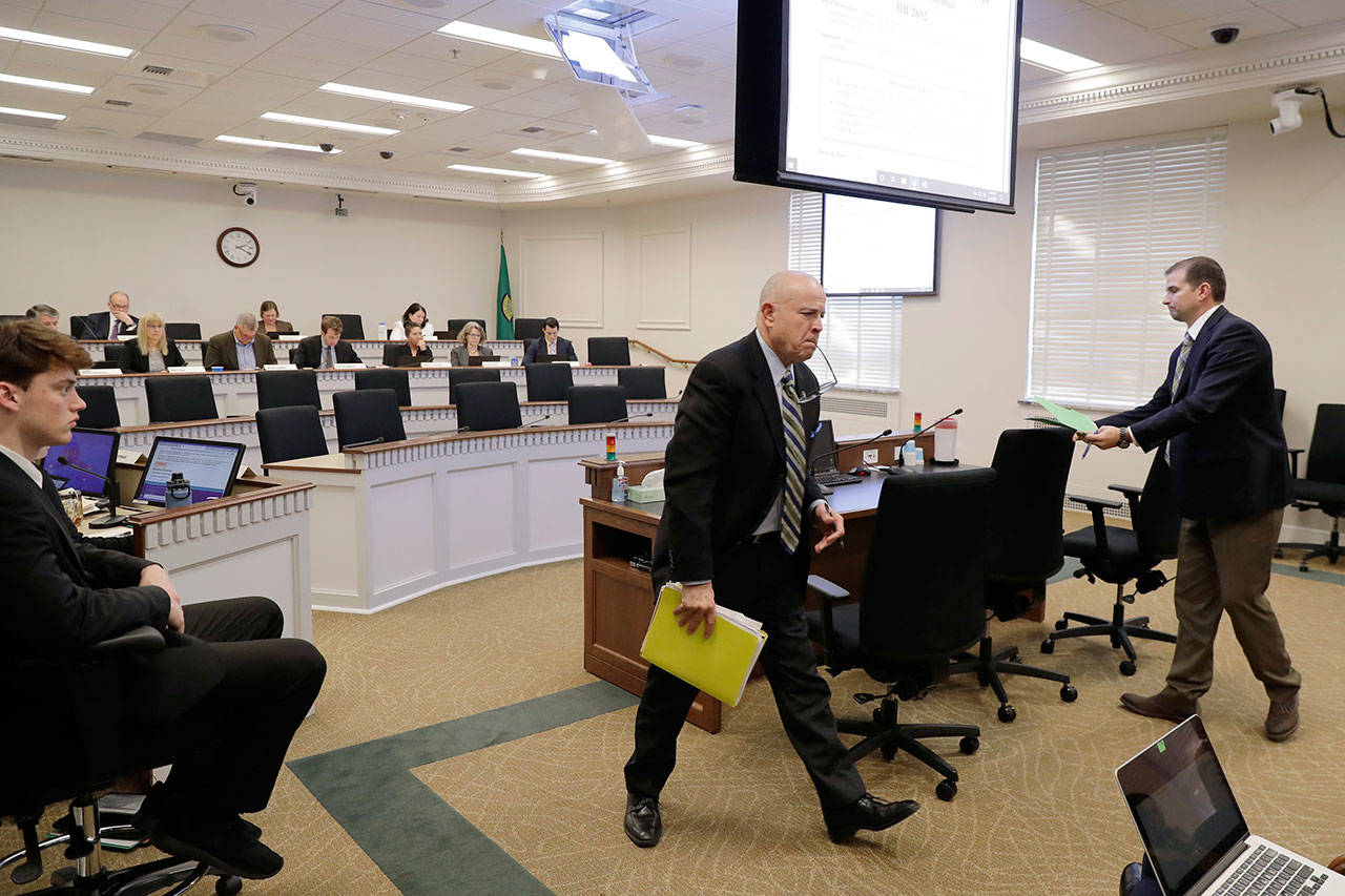 Greg Hanon, center, who represents the Western States Petroleum Association, gets up after speaking during a hearing of the Washington State House of Representatives Environment and Energy Committee on Monday, Feb. 3, 2020, at the Capitol in Olympia. Hanon spoke in opposition to a House bill that seeks to fully reinstate Washington Gov. Jay Inslee’s plan to cap carbon pollution in Washington by giving additional regulatory authority to the state Department of Ecology. (Ted S. Warren/The Associated Press)