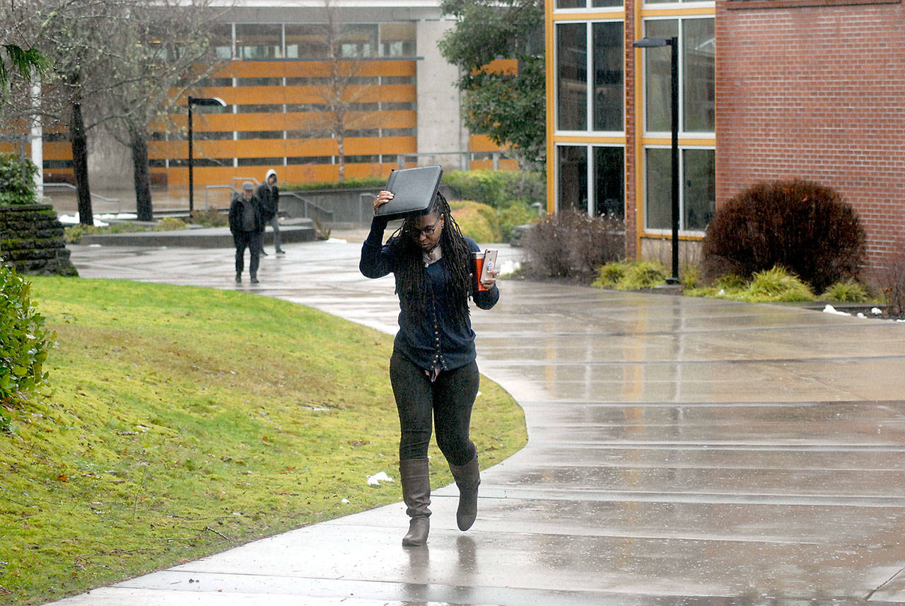 Nitasha Lewis, a manager with the Upward Bound program at Peninsula College, uses a paper valise to keep her head dry as she walks across the college’s Port Angeles campus Thursday, Feb. 6, 2020. Persistent rains, heavy at times, stalled across areas of the North Olympic Peninsula on Thursday, leading to flood watches and warnings and a danger for landslides. Conditions are expected to improve by Sunday, with a chance for dry weather and sunshine into early next week. (Keith Thorpe/Peninsula Daily News)