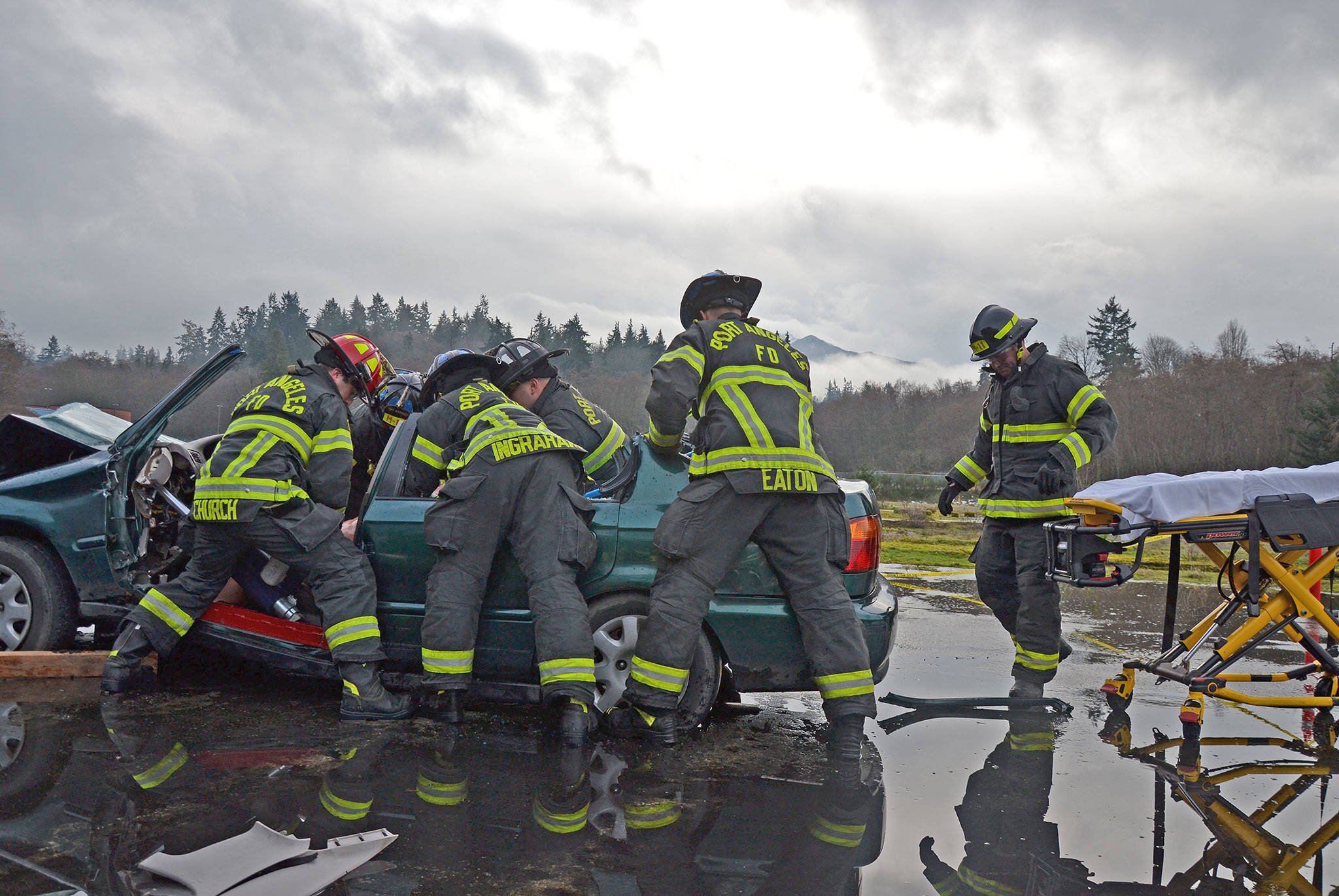 The Port Angeles Fire Department B Shift works together during a recent drill at the old Rayonier site in Port Angeles. The crew was tasked with quickly and efficiently extracting a “victim” from the donated car. (Laura A. Foster/Peninsula Daily News)