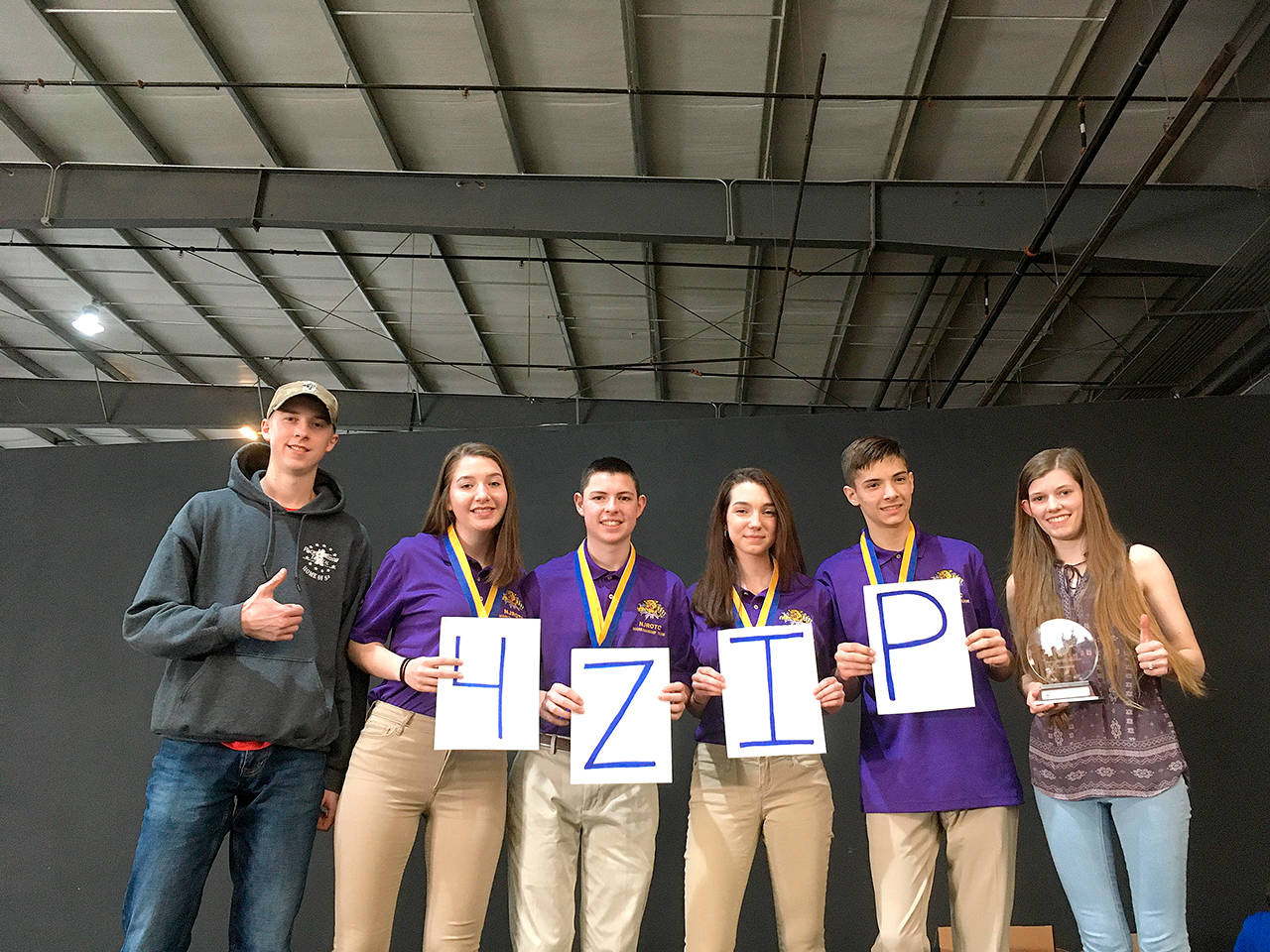 Shooters Trevor Westman, left, Lauren Crossley, James Hart, Alexis Kunze and Port Angeles’ Cheyenne Maggard give a shoutout to coach Dave “Zip” Goodman, who could not attend the NJROTC championships with them. (Submitted photo)