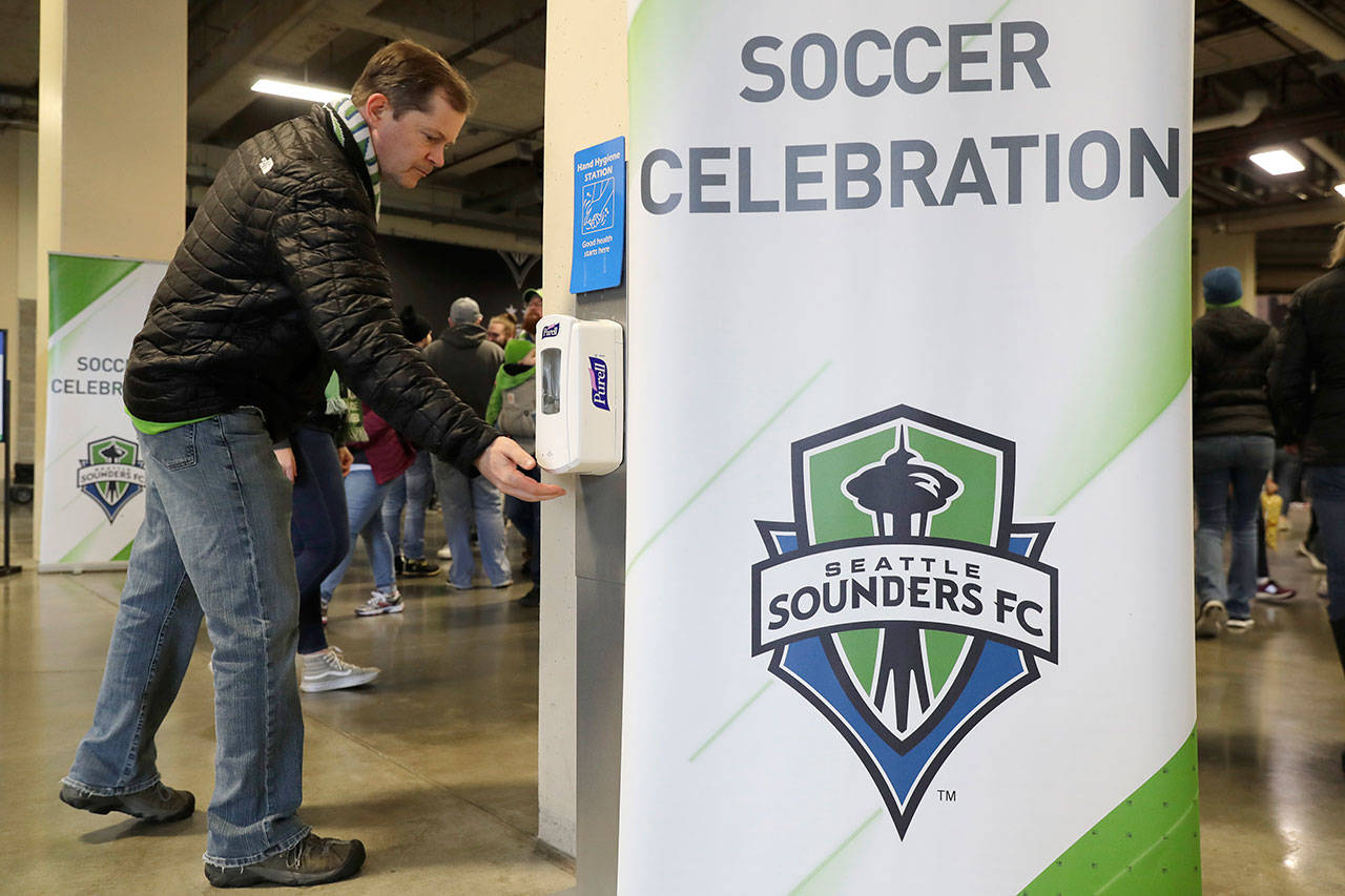 A man makes use of a hand-sanitizing station at CenturyLink Field prior to an MLS soccer match between the Seattle Sounders and the Chicago Fire on Sunday, March 1, 2020, in Seattle. Major North American professional sports leagues are talking to health officials and informing teams about the coronavirus outbreak. (Ted S. Warren/The Associated Press)