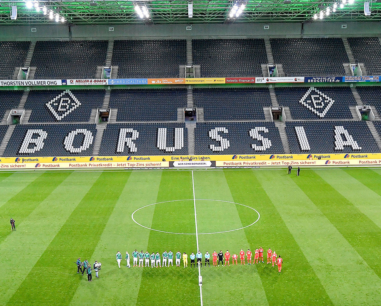 Players stand in an empty stadium prior the last German Bundesliga soccer match prior the coronavirus break between Borussia Moenchengladbach and 1.FC Cologne in Moenchengladbach, Germany, Wednesday, March 11, 2020. For most people, the new coronavirus causes only mild or moderate symptoms, such as fever and cough. For some, especially older adults and people with existing health problems, it can cause more severe illness, including pneumonia. (AP Photo/Martin Meissner)