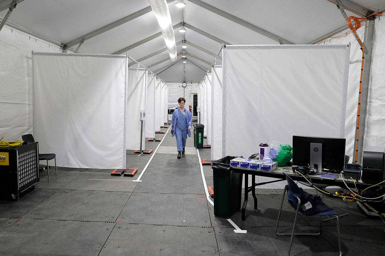 Forest Gauthier, an emergency services medical assistant, walks through a tent set up outside the Emergency Department at the Harborview Medical Center before it opened for patients Thursday, April 2, 2020, in Seattle. The tent, which was recently put in place, is used to examine walk-up and other patients who arrive at the emergency room with respiratory symptoms possibly related to the new coronavirus. (Ted S. Warren/The Associated Press)