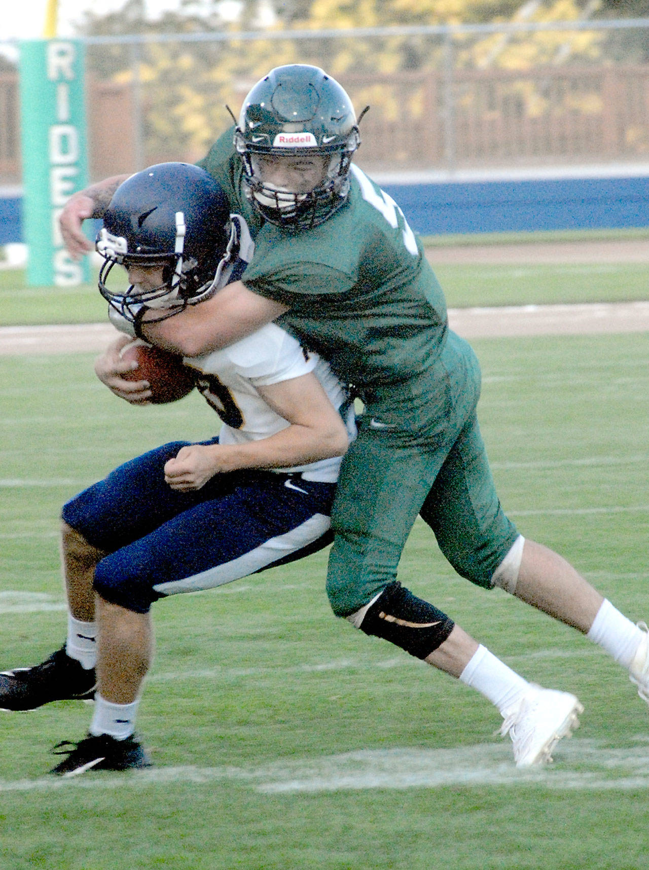 Forks wide receiver Logan Olson is wrapped up by Port Angeles’ Tyler Bowen in September 2019. Bowen has signed a letter of intent to play football for the University of Puget Sound. (Keith Thorpe/Peninsula Daily News file)