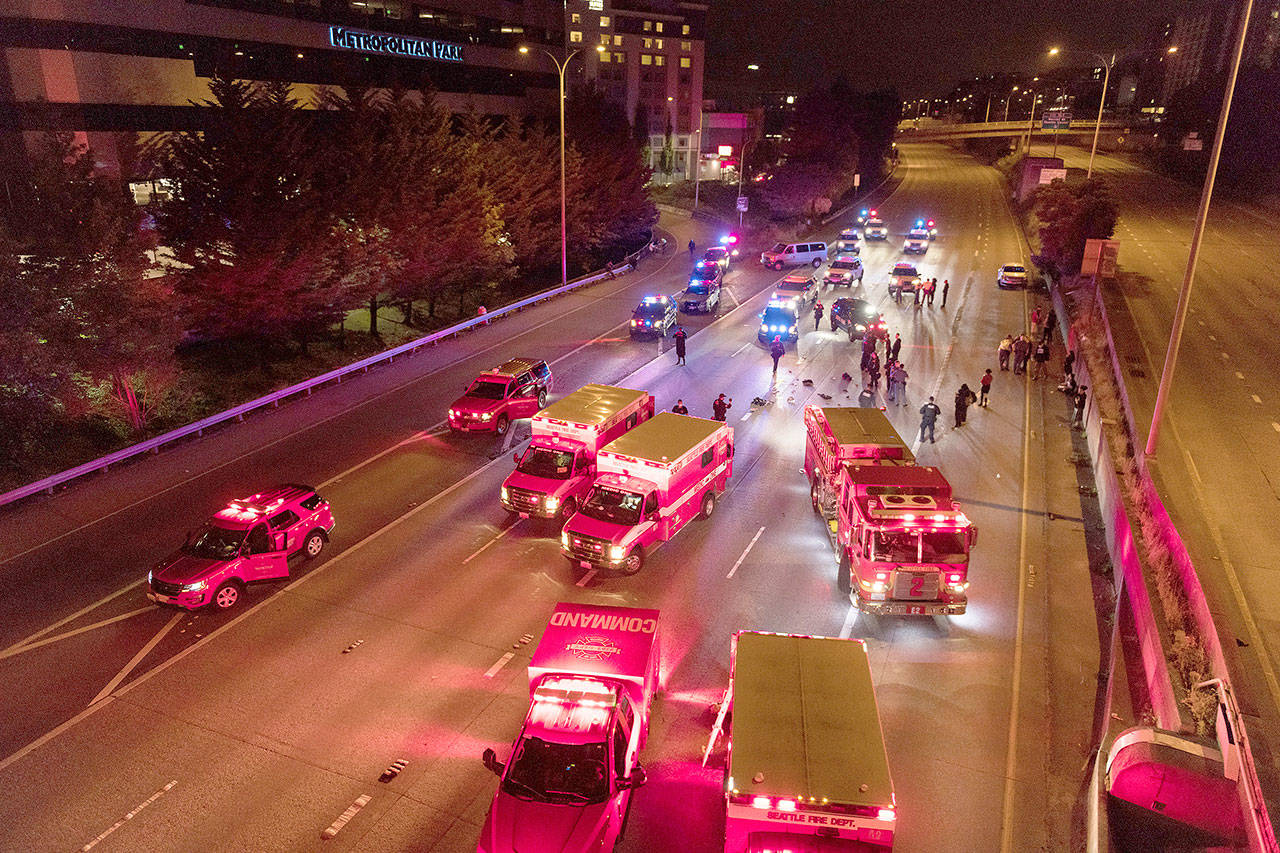 Emergency personnel work at the site where a driver sped through a protest-related closure on the Interstate 5 freeway in Seattle, authorities said early Saturday, July 4. (James Anderson via The Associated Press)