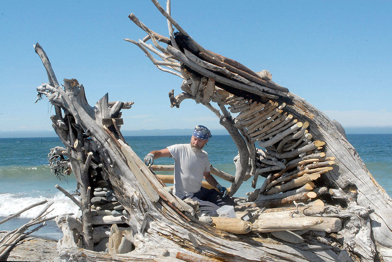 Sky Darwin of Port Angeles works on Saturday, July 18, 2020, to reconstruct the heart sculpture that was burned last spring on Ediz Hook along the Strait of Juan de Fuca. (Keith Thorpe/Peninsula Daily News)