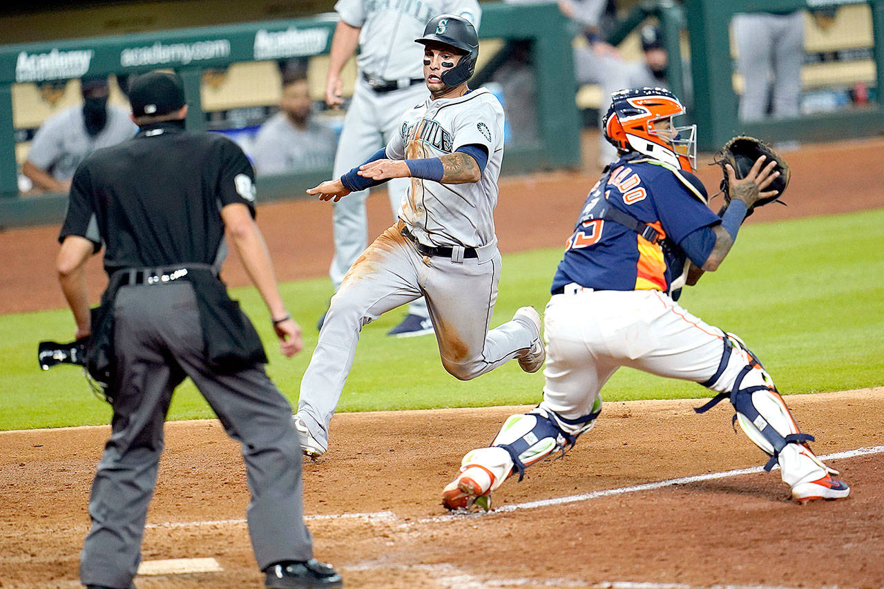 Seattle Mariners’ Tim Lopes, center, avoids Houston Astros catcher Martin Maldonado to score a run during the eighth inning of a baseball game Sunday, July 26, 2020, in Houston. (AP Photo/David J. Phillip)