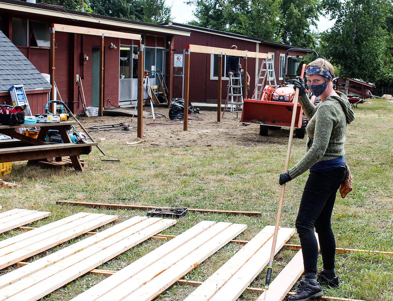 Head of School Emily Gohn stains fence planks for a new outdoor preschool area.