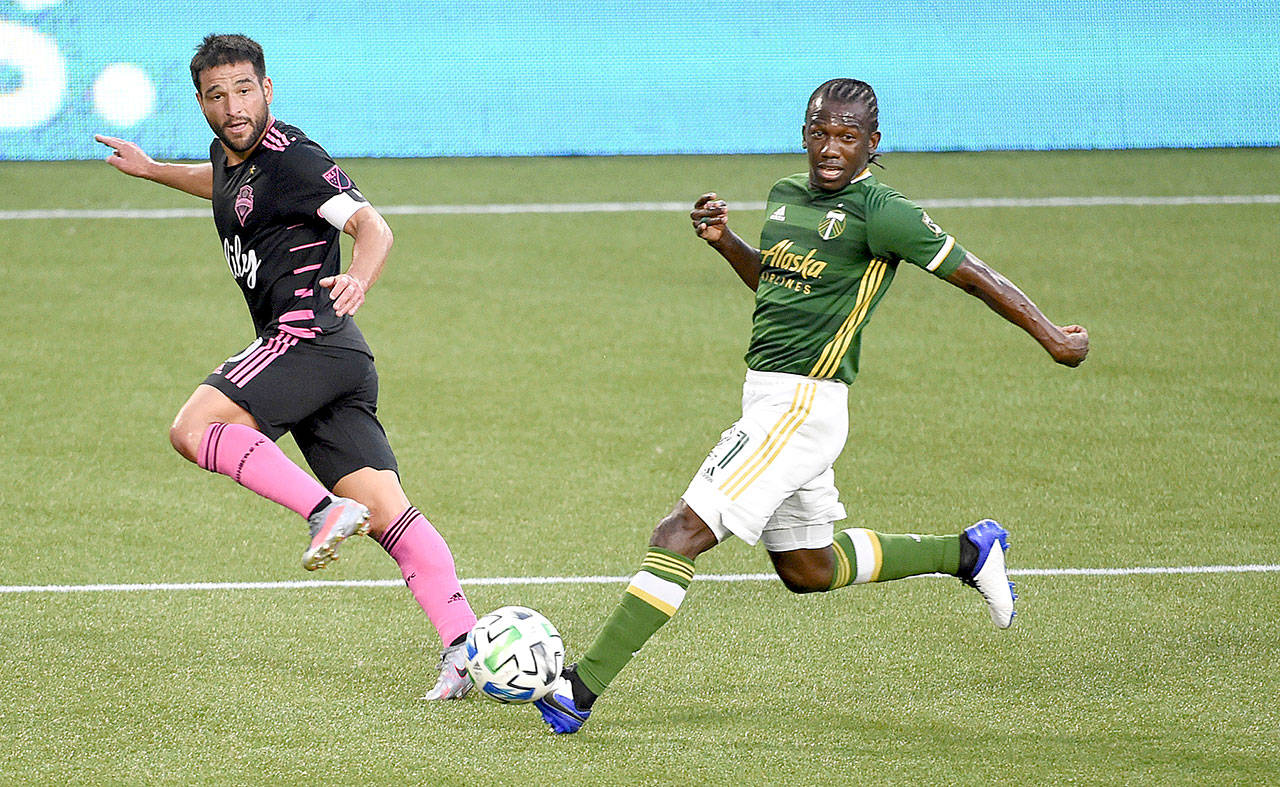 Seattle Sounders midfielder Nicolas Lodeiro, left, passes the ball past Portland Timbers midfielder Diego Chara during the first half of an MLS soccer match in Portland, Ore., on Sunday, Aug. 23, 2020. (Steve Dykes/Associated Press)