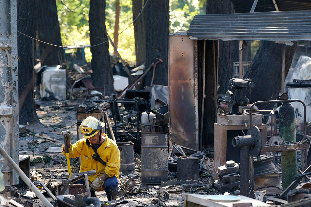 A firefighter working to put out hotspots pauses in the rubble of a structure destroyed by fire Tuesday, Sept. 8, 2020, after an overnight wildfire in Graham, Wash., overnight south of Seattle. (Ted S. Warren/Associated Press)