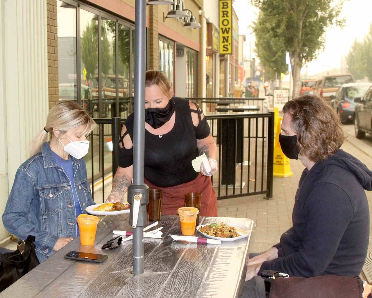 Brenda Lane, left, and her husband Aaron Coberly of Redmond are served food by Monica Farris outside the New Day Eatery on Front Street in downtown Port Angeles. The couple adventured to the Peninsula for their anniversary. (Dave Logan/for Peninsula Daily News)