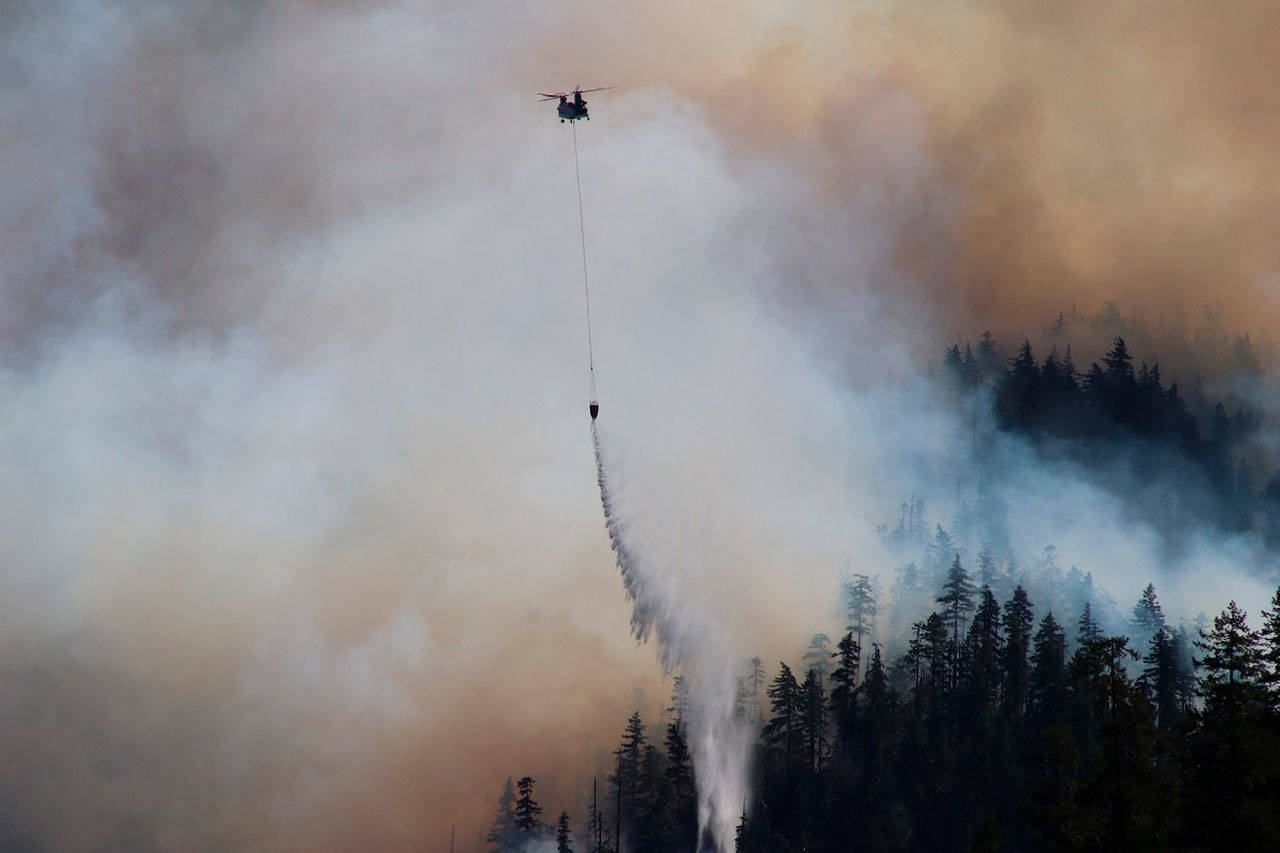 In this Sept. 3, 2020, photo provided by the Opal Creek Ancient Forest Center, fire retardant is dropped at Jawbone Flats in the Opal Creek Wilderness in Oregon. Oregonians are grieving the loss of some of their most treasured natural places after wildfires wiped out campgrounds, hot springs and wooded retreats that have been a touchstone for generations in a state known for its unspoiled beauty. (Augustus Gleason/Opal Creek Ancient Forest Center via AP)