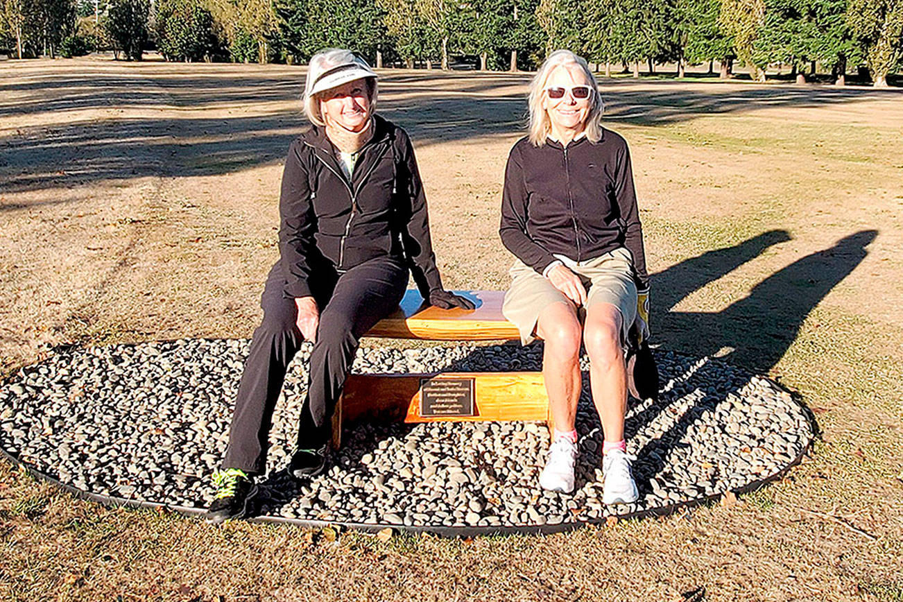 Dee Sweeney (L), Captain, Discovery Bay Women's Golf Club and Katherine Buchanan (R), Captain, Port Townsend Women's Golf Club sitting on the newly installed memorial bench in honor of Naomi and Janie Marcus at Port Townsend Golf Course. (photo below)