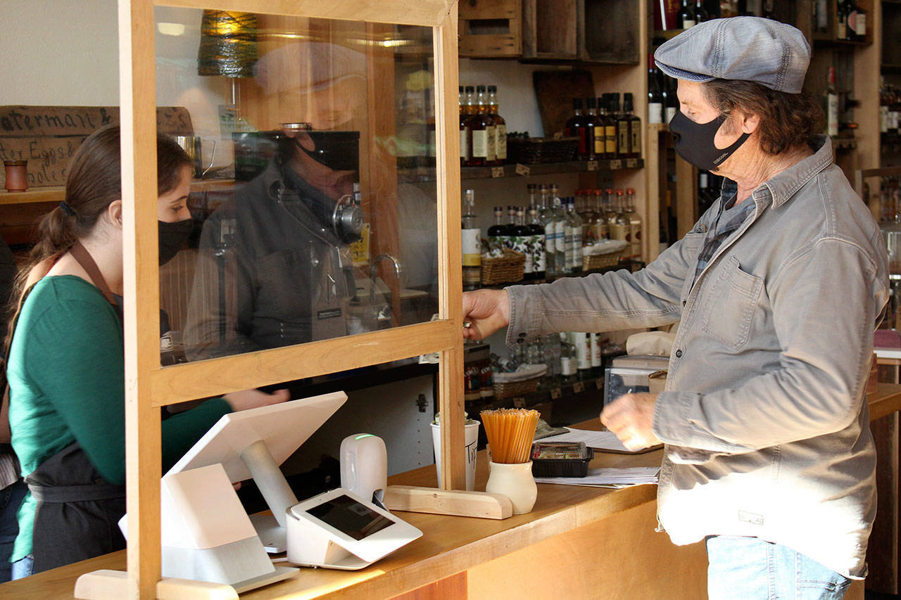 Port Townsend resident Mike Marston checks out of Aldrich’s Market on Tuesday, Oct. 13, 2020, with barista and cashier Sarah Marx. The 125-year-old store reopened Saturday after closing in early spring and after being bought by new owners who renovated the business over the summer. (Zach Jablonski/Peninsula Daily News)