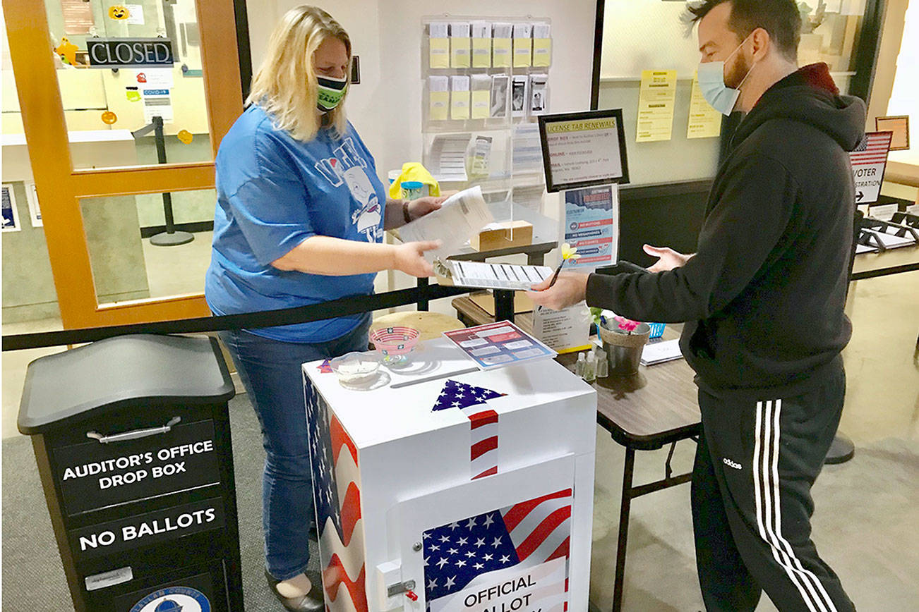 Angi Klahn, left, Clallam County Auditor's Office accountant, helped process voter registration Friday for Seth Russell, formerly of Santa Cruz, Calif., who recently moved to Port Angeles with his partner and her brother. (Paul Gottlieb/Peninsula Daily News)