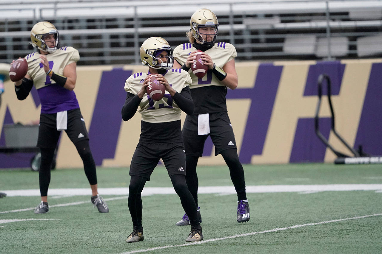 Washington quarterbacks Jaden Sheffey, center, Kevin Thomson, left, and Jacob Sirmon, right, pass in a group during NCAA college football practice Friday, Oct. 16, 2020, in Seattle. (Ted S. Warren/Associated Press)