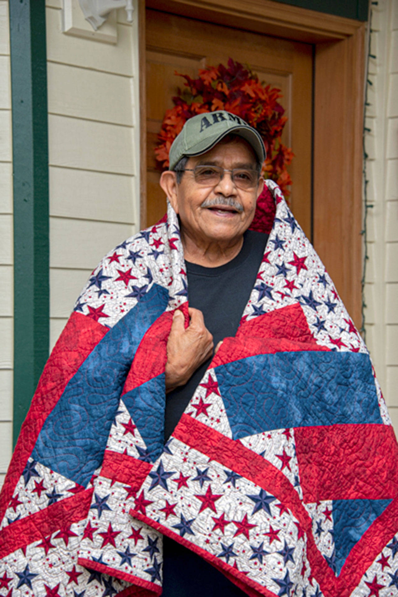 Daniel J. Merino, U.S. Army veteran, is wrapped in the quilt that was recently made for and presented to him by the North Olympic Peninsula Quilts of Valor group. (Photo courtesy of Christopher Bates Photography)