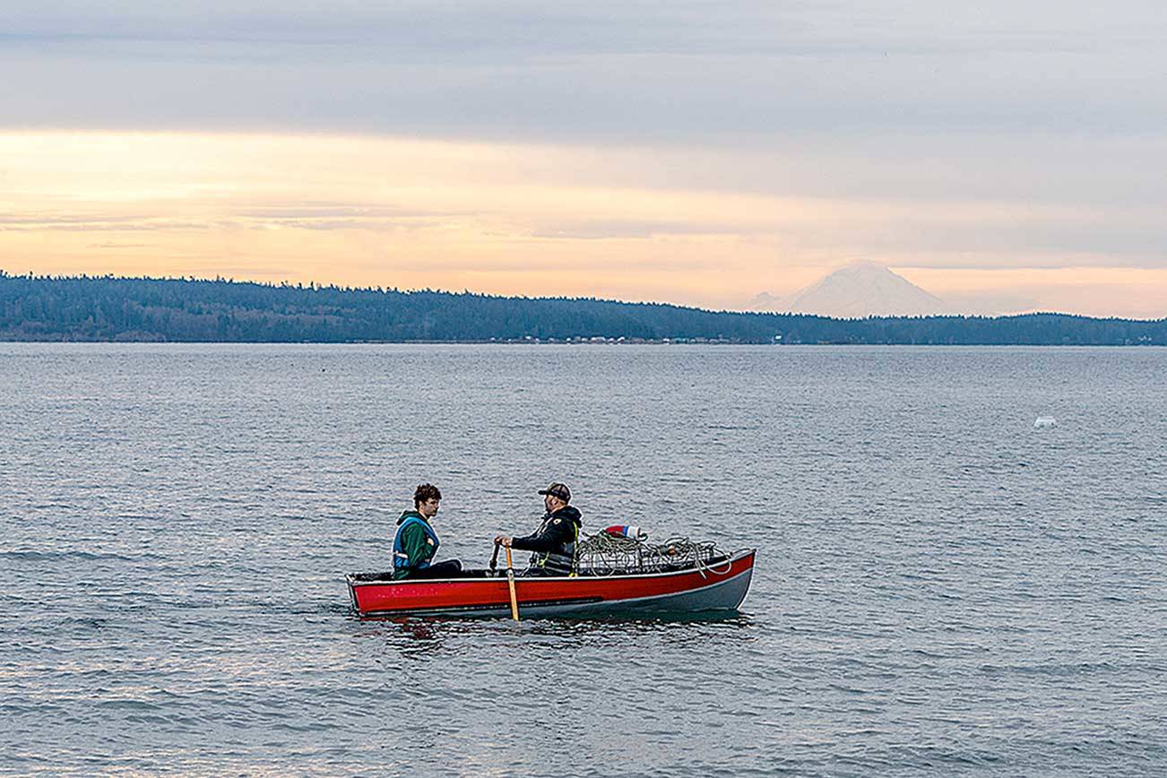 With Mount Rainier for a backdrop, Jason Warner, rowing, and his son, Jackson, from Bremerton, row to shore Sunday with empty crab pots following a weekend camping trip to Fort Worden State Park. (Steve Mullensky/for Peninsula Daily News)