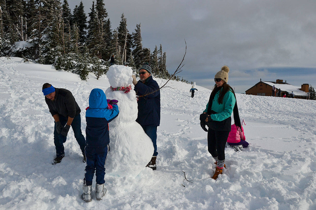 The Roubik Family builds upon a pre-exisiting snowman in the kids’ sledding area at Hurricane Ridge on Nov. 27, 2020. From left  is David, Maya, 6, grandfather David, Liz Jones and Vera, 8. (Laura Foster/Peninsula Daily News)