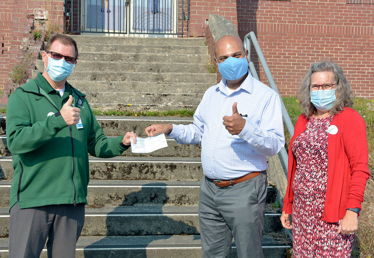 Superintendent Marty Brewer, on left, receives a check from Ray Chirayath, center, and Lynn Bedford, on right, of the Port Angeles Education Foundation. The $50,000 grant will assist students who have difficulty accessing the internet from home in order to participate in distance learning. (Submitted photo)