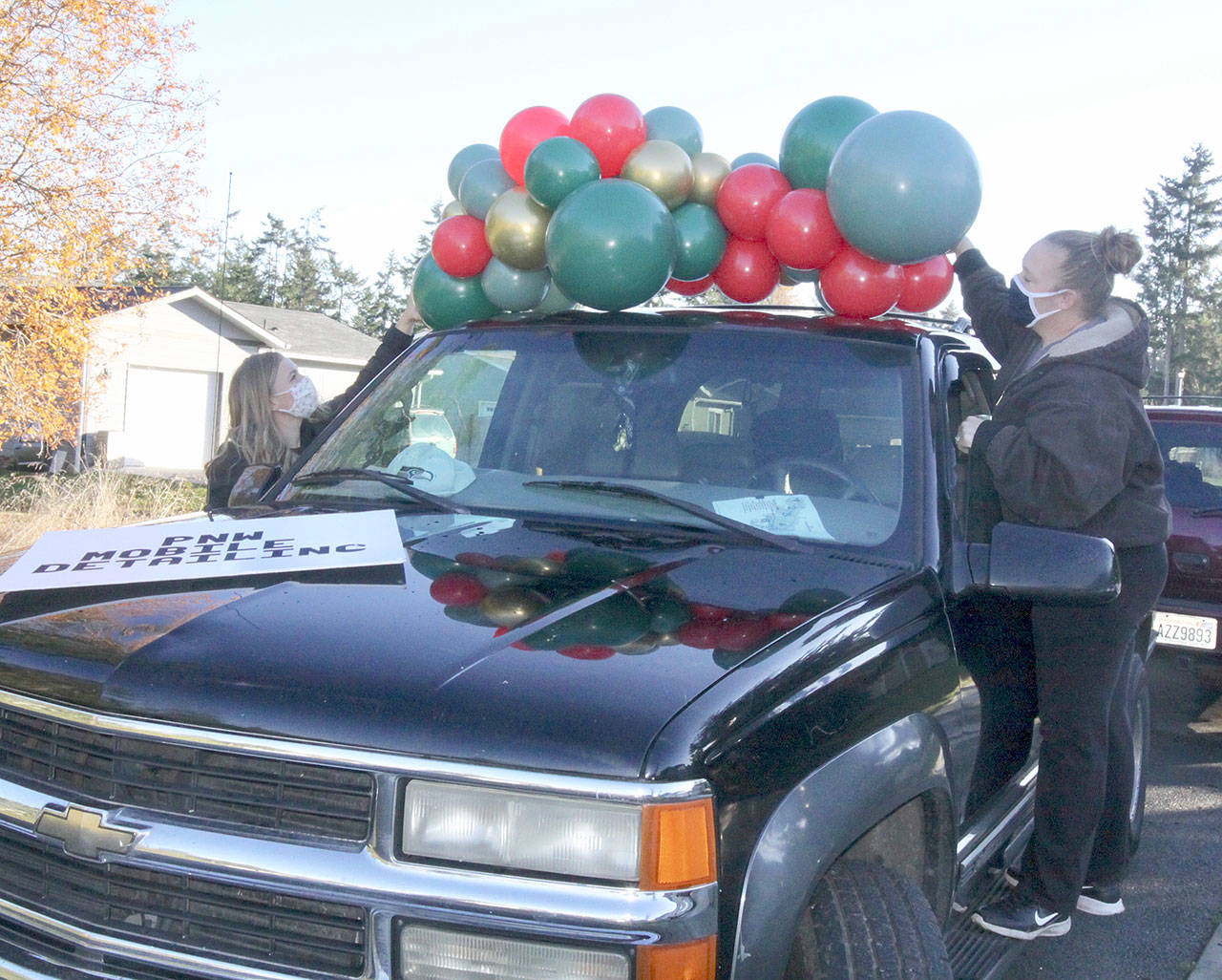 Chelsey Bettger, of Joyful Events and Balloons, left, and Katheryn Murray, of PNW Mobile Detailing, decorate one of the vehicles to be used in the Candy Cane Parade of Happiness. (Dave Logan/for Peninsula Daily News)