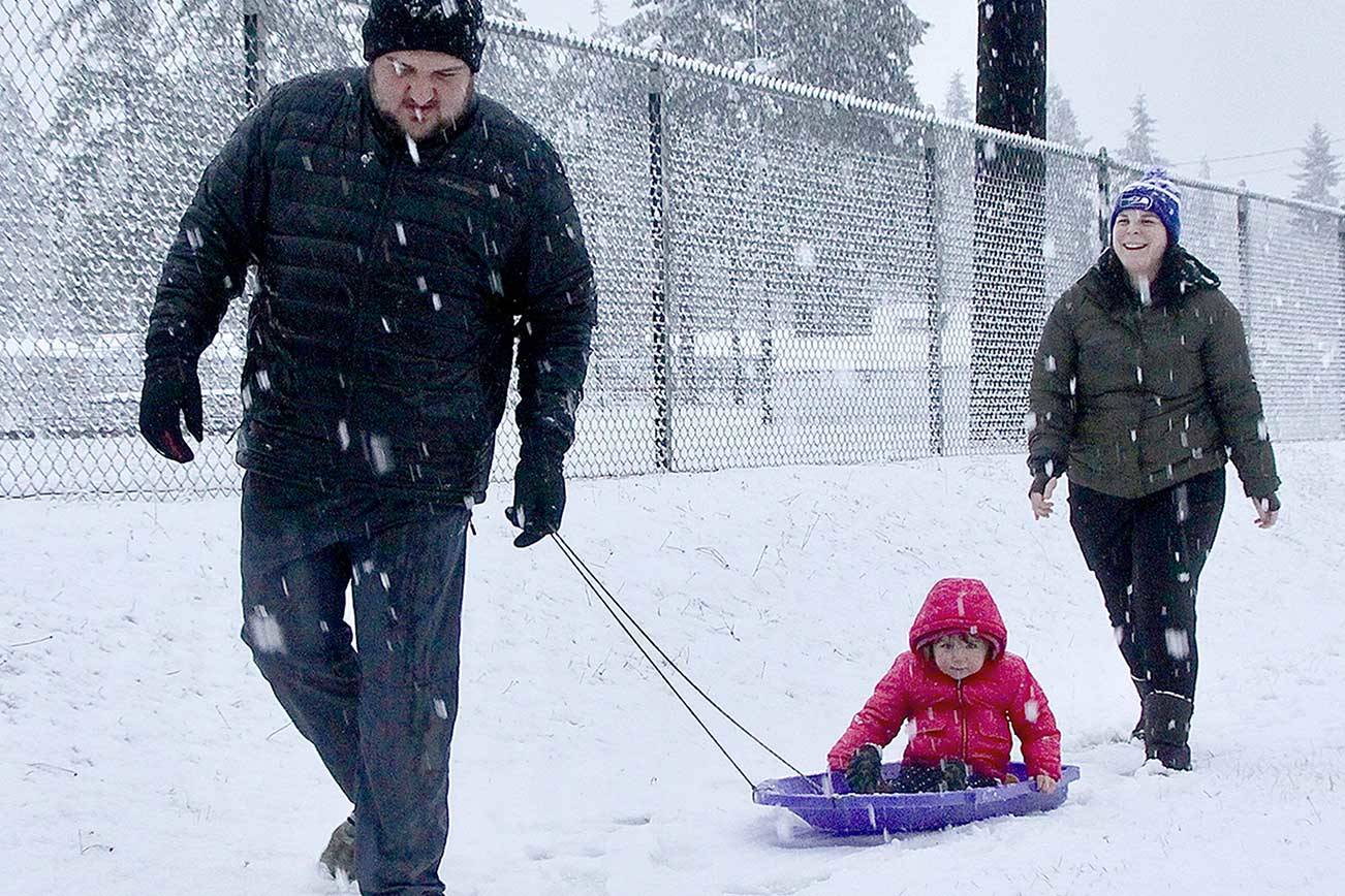 Jarrett and LeAnn Hansen took their daughter H.J., 2, out sliding just outside the fence of Elks Playfield on Pine Street on Monday during the first snow of the winter. (Dave Logan/For Peninsula Daily News)