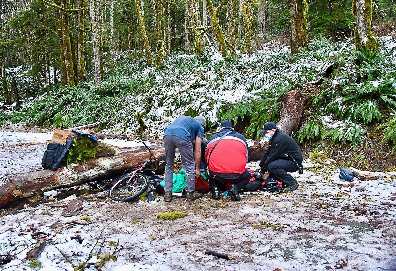 Rescue workers attend to a man who was injured after he was struck by a falling tree while he was riding his bicycle in the Elwha Valley. (Photo courtesy of Clallam County Fire District 2)