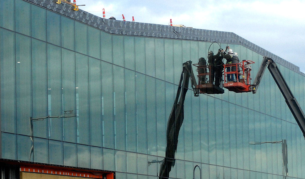 A construction crew works on the glass face of the new Field Arts & Events Hall on Thursday near the Port Angeles waterfront. The hall is expected to be put on hold when the exterior is complete pending additional fundraising to finish the approximately $50 million project, which will include a 1,000-square-foot art gallery, 500-seat performance hall, 300-seat conference area and a coffee shop. (Keith Thorpe/Peninsula Daily News)