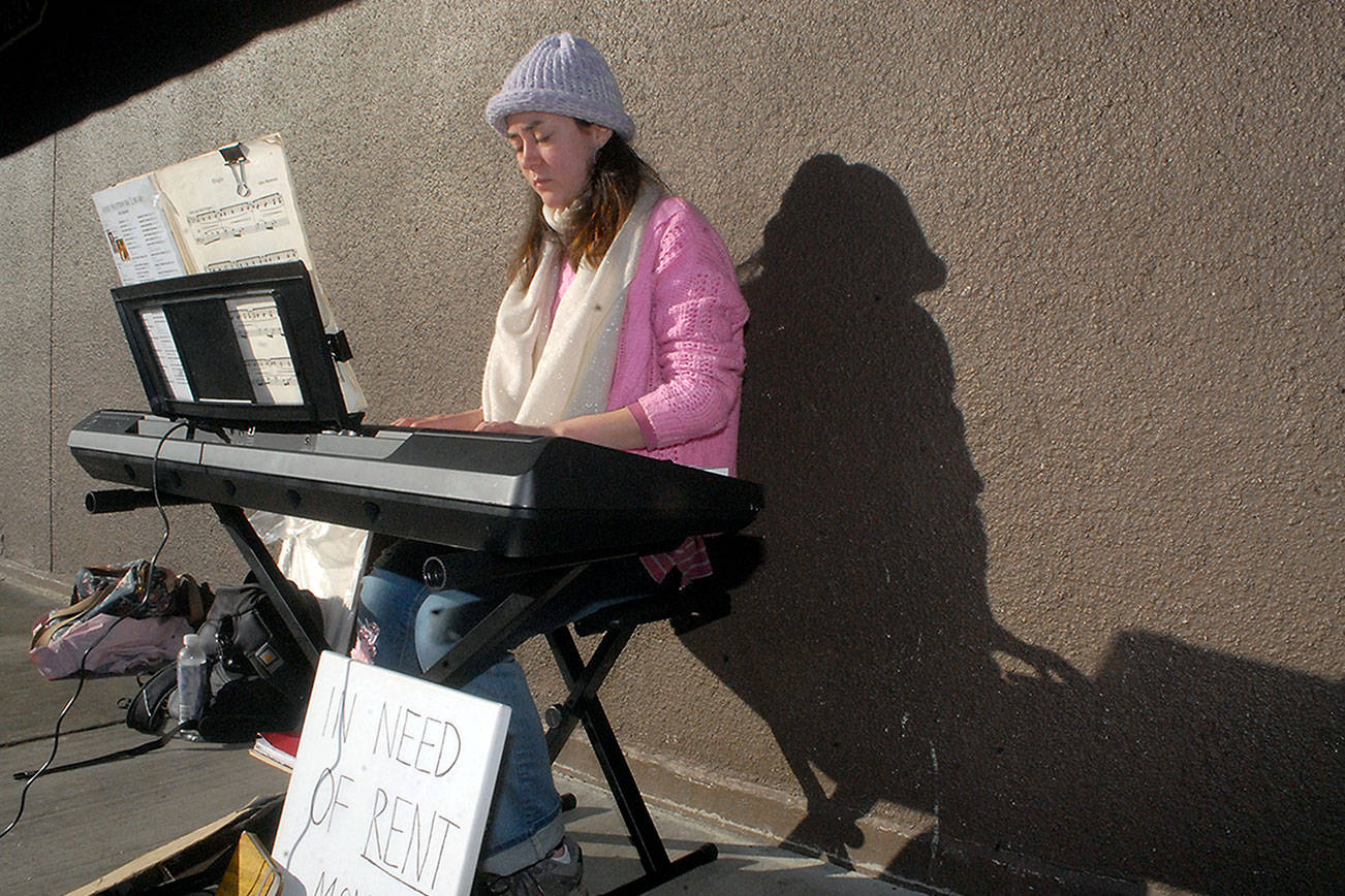 Raisa Mathisen of Port Angeles performs on an electric piano in the 100 block of South Oak Street next to Country Aire in downtown Port Angeles on Saturday. Mathisen said she was busking to help cover living expenses. (Keith Thorpe/Peninsula Daily News)