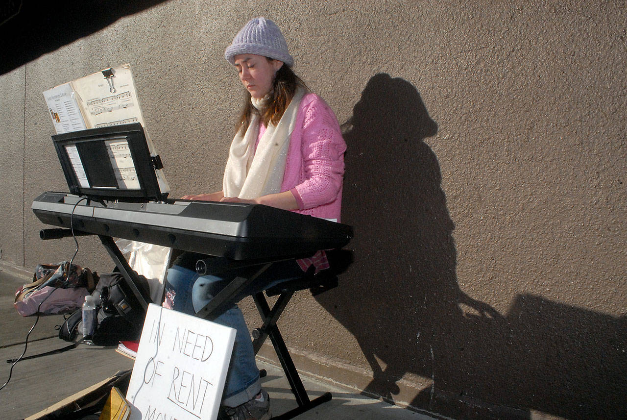 Raisa Mathisen of Port Angeles performs on an electric piano in the 100 block of South Oak Street next to Country Aire in downtown Port Angeles on Saturday. Mathisen said she was busking to help cover living expenses. (Keith Thorpe/Peninsula Daily News)