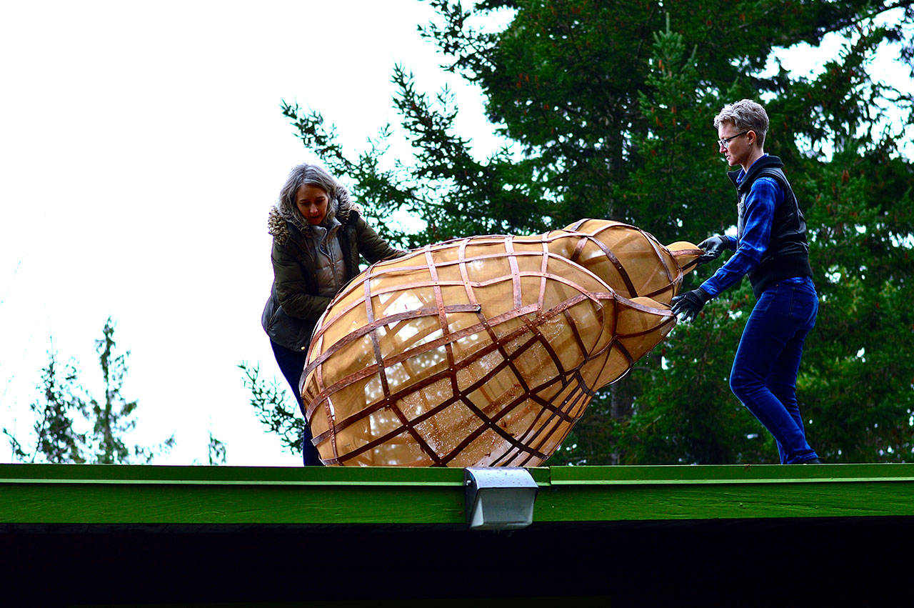 Port Angeles Fine Arts Center gallery and program director Sarah Jane, right, helps fellow artist Katherine Shaughnessy position her installation, “Tempest Tost,” on the roof of the arts center in late 2019. The piece is back on the roof for this season’s Wintertide show in and around the Webster’s Woods park. (Diane Urbani de la Paz/Peninsula Daily News)