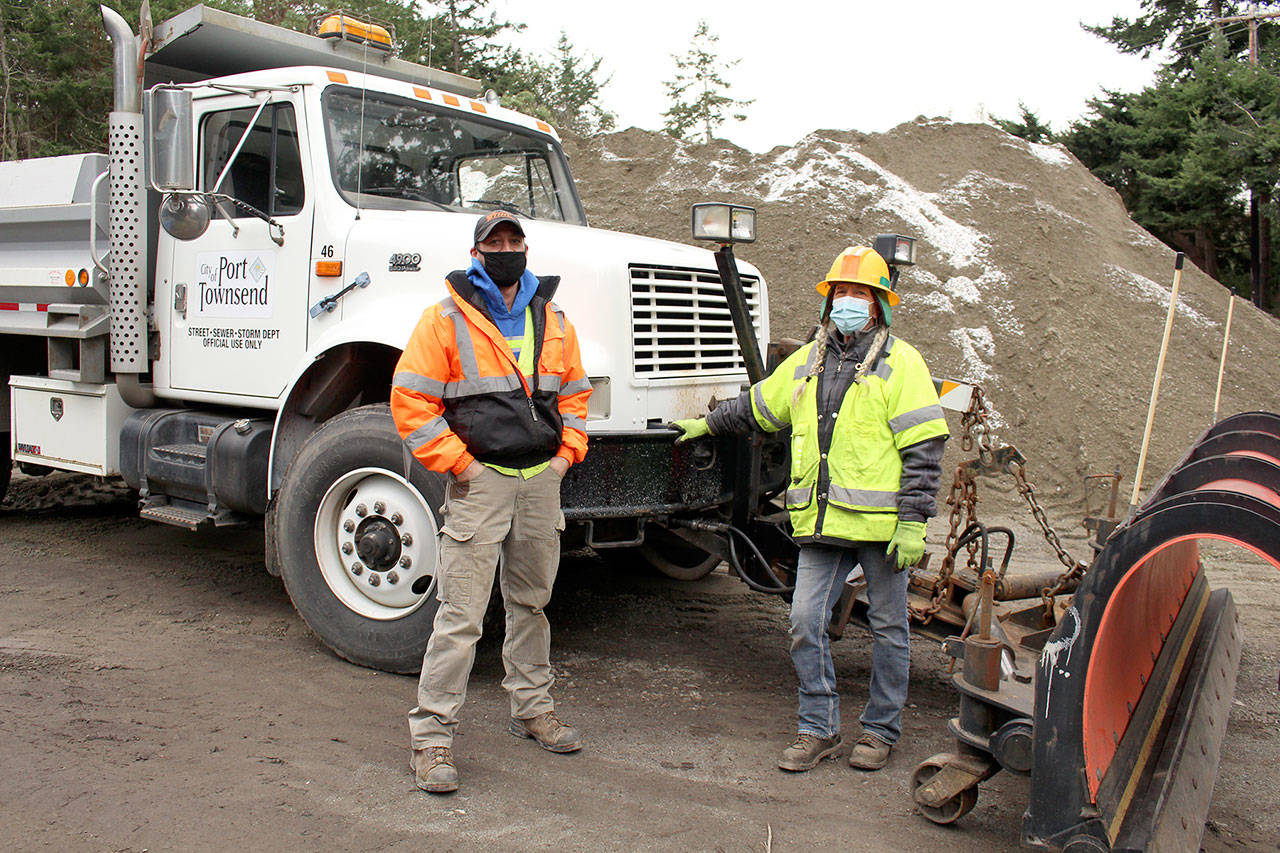 Port Townsend Public Works Crew Chief Chris MacDonald, left, stands with Tracy Benson, equipment operator, on Wednesday in front of one of the snow plows they and their other team members will use to keep roads clear in Port Townsend. Snow is forecast in the next few days. (Zach Jablonski/Peninsula Daily News)