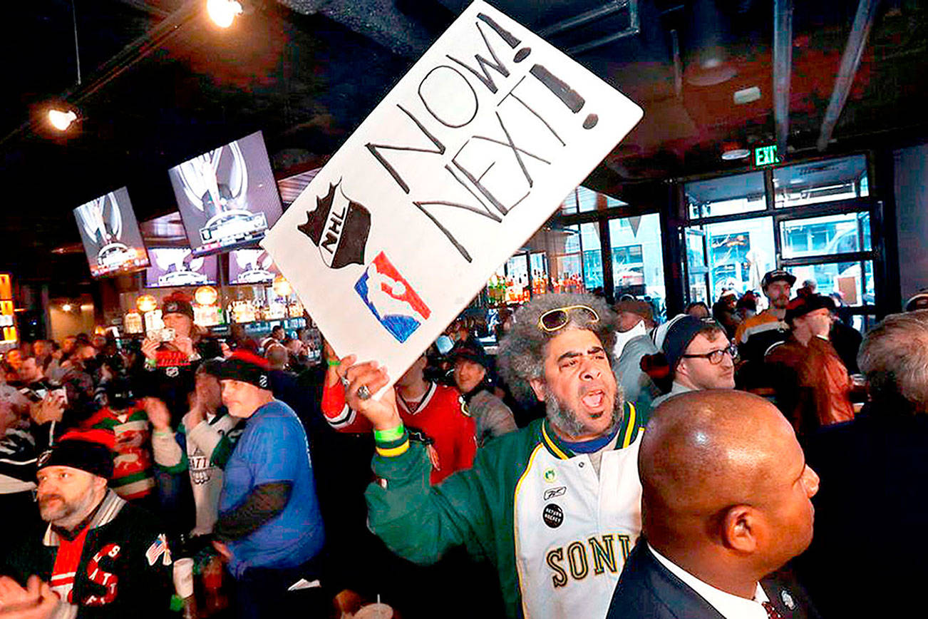 The late Kris “Sonic Guy” Brannon holds up a sign in support of adding an NBA team following the announcement of a new NHL hockey team in Seattle, at a celebratory party Tuesday, Dec. 4, 2018, in Seattle. (AP Photo/Elaine Thompson) ELAINE THOMPSON AP